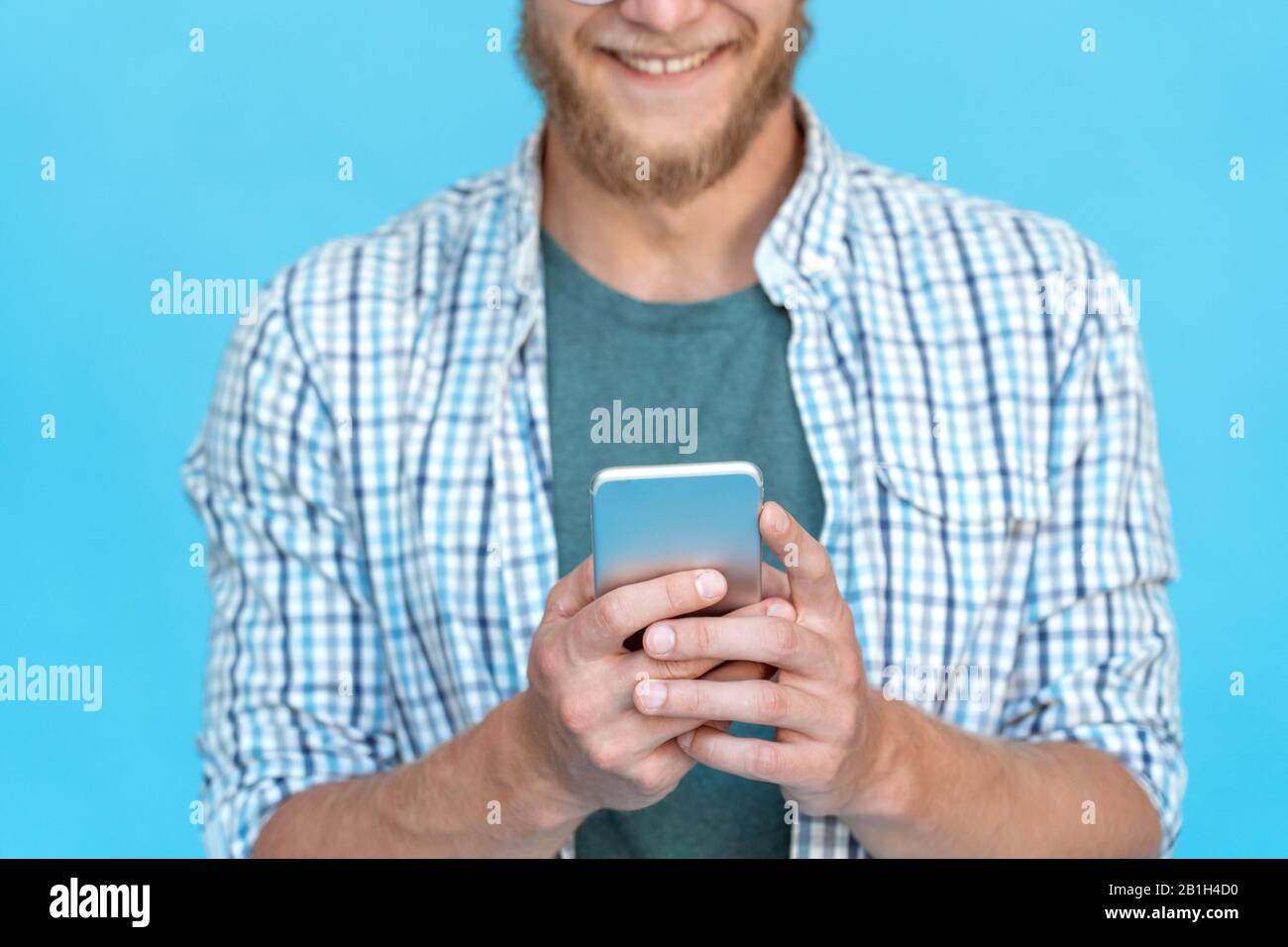 Gros plan barbu jeune homme utiliser moderne smartphone sourire message texte chat en ligne Banque D'Images