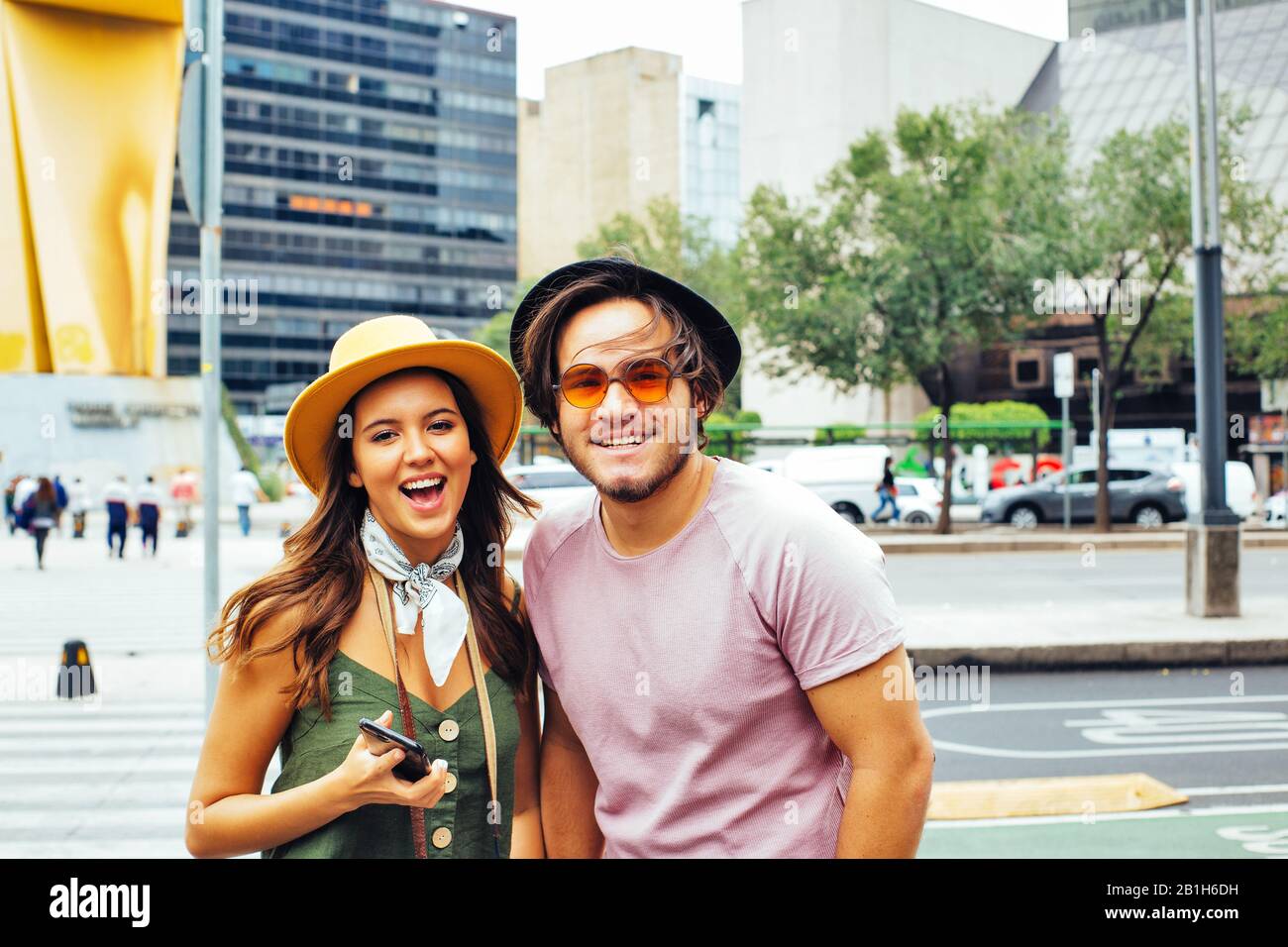 Portrait de jeunes heureux couple de touristes branchés avec des chapeaux souriant à l'appareil photo à Mexico Banque D'Images