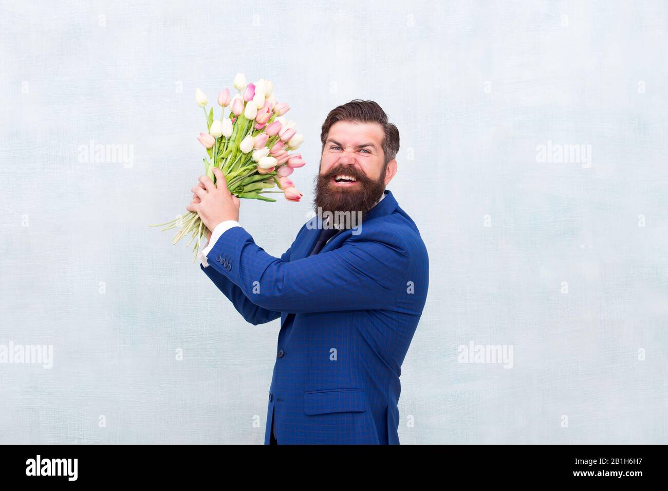 Homme barbu en colère avec des fleurs. Fêtez le printemps. Échec de la date. Irritée, l'homme barbu agacé avec bouquet de tulipes. Concept déçu. Date d'échec. Des vacances de haine. Journée pour femme. 8 Mars. Banque D'Images