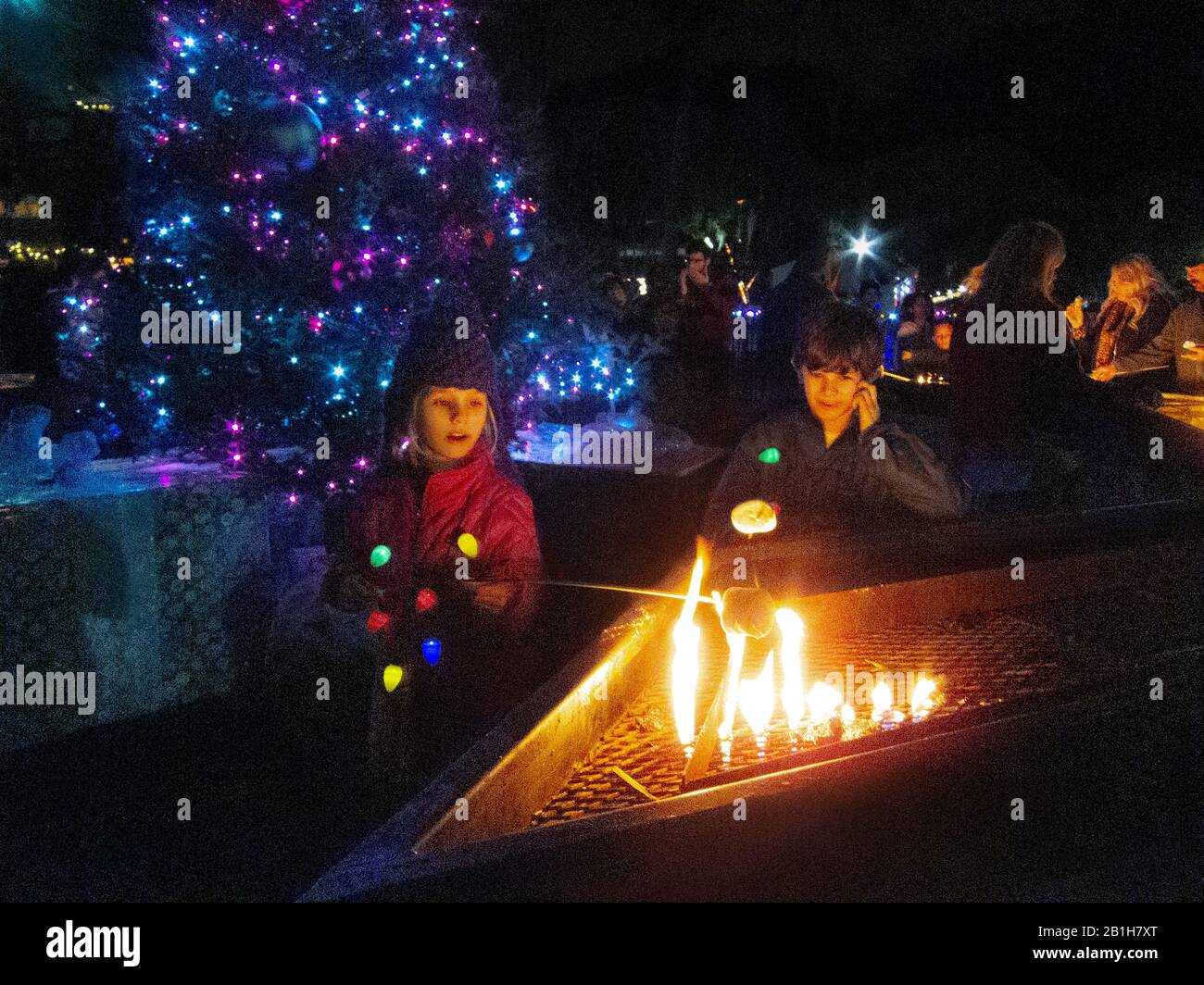 Deux enfants qui toasting des guimauves au parc de la ville pendant la saison de Noël. La Nouvelle-Orléans, LA. Banque D'Images
