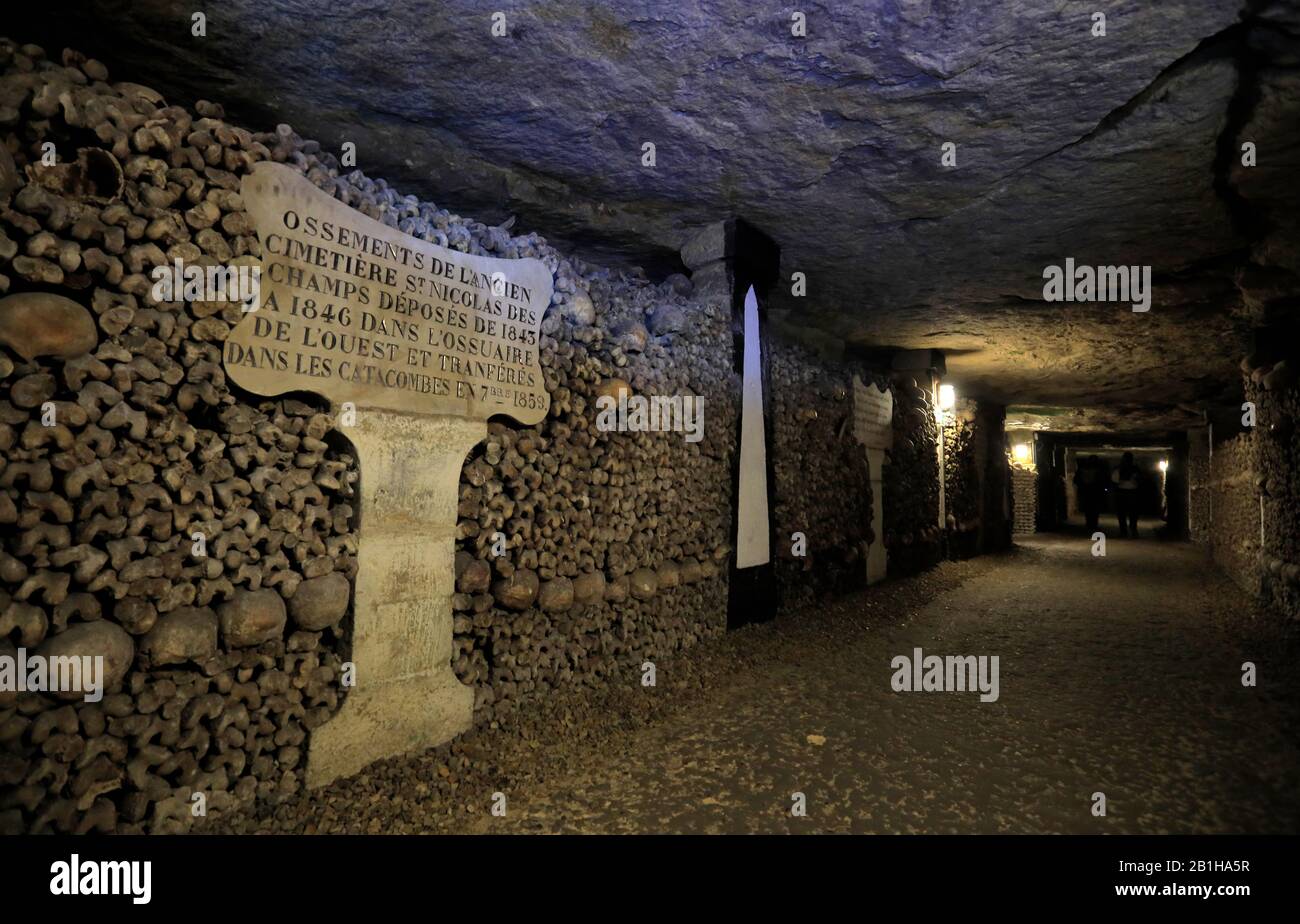 Os et crânes stockés à l'intérieur des catacombes de Paris avec la tablette en pierre indiquant le cimetière d'origine où ils sont enterrés .Paris, France Banque D'Images