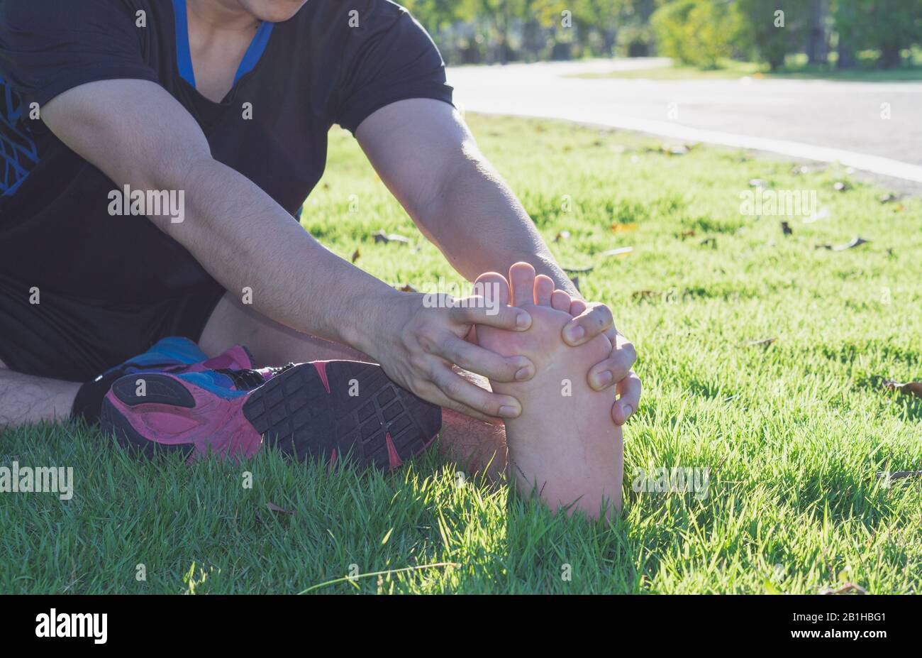 Jeune homme masser son pied douloureux de marcher et courir sur une piste de course. Concept du sport et de l'exercice. Banque D'Images