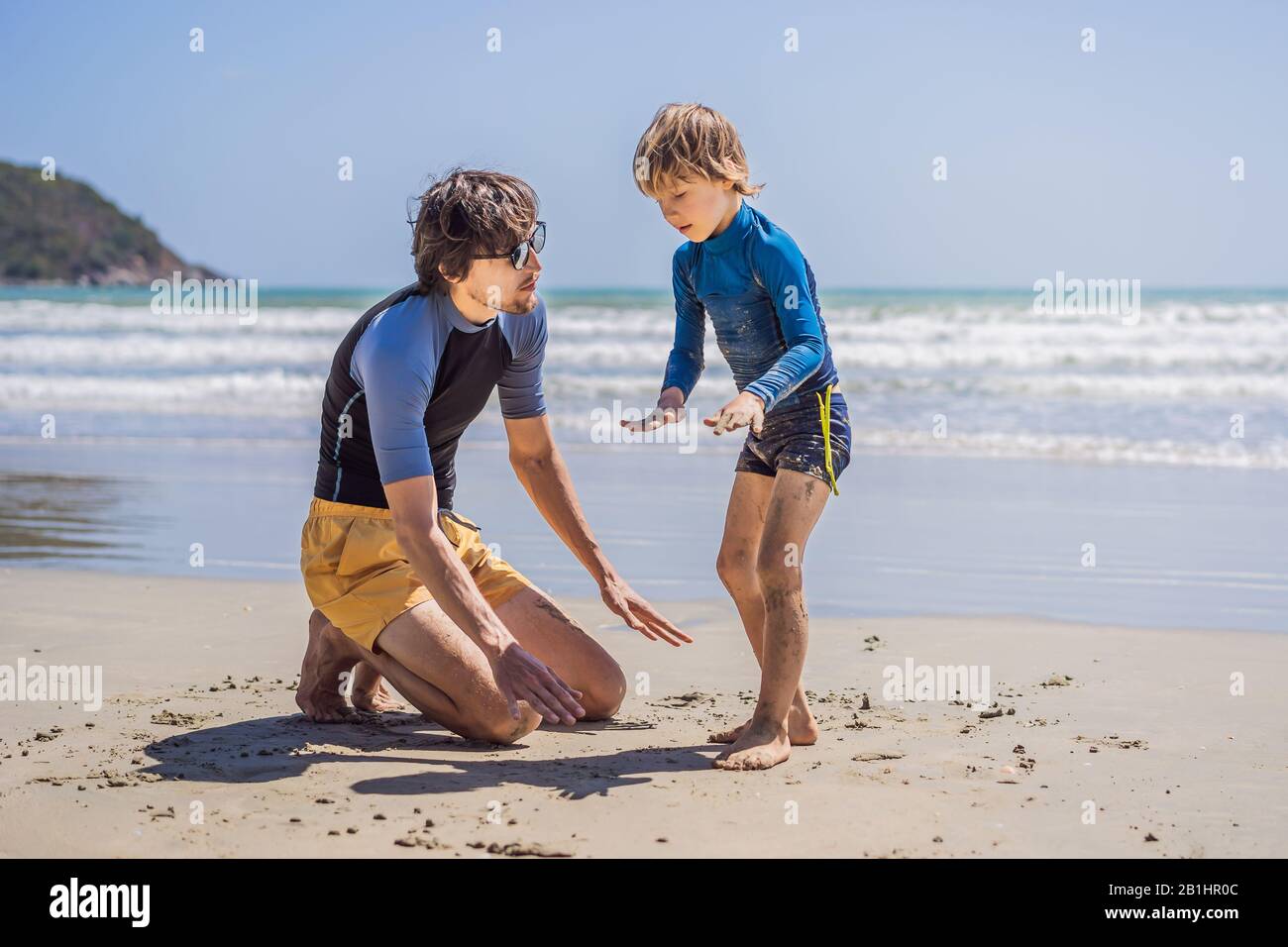 Père ou instructeur enseignant à son fils comment surfer dans la mer en vacances ou en vacances. Voyage et sport avec concept enfants. Cours de surf pour les enfants Banque D'Images