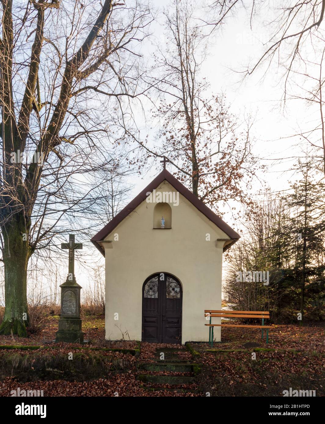 Petite chapelle avec croix en pierre ancienne, banc en bois et arbres autour du village de Cermna ve Slezsku en république tchèque Banque D'Images