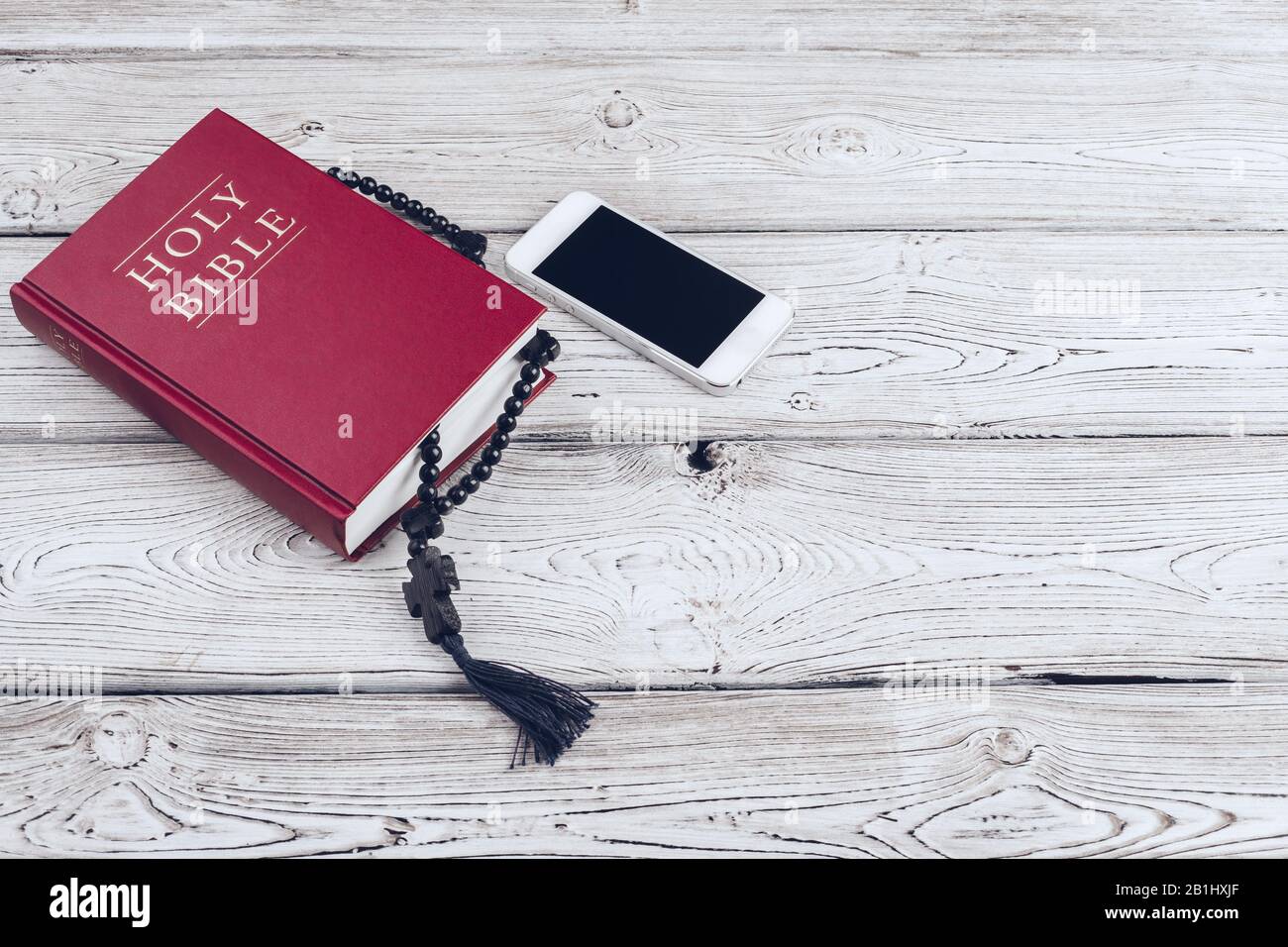 Bible Sainte et smartphone avec tasse de café noire sur fond en bois. Banque D'Images