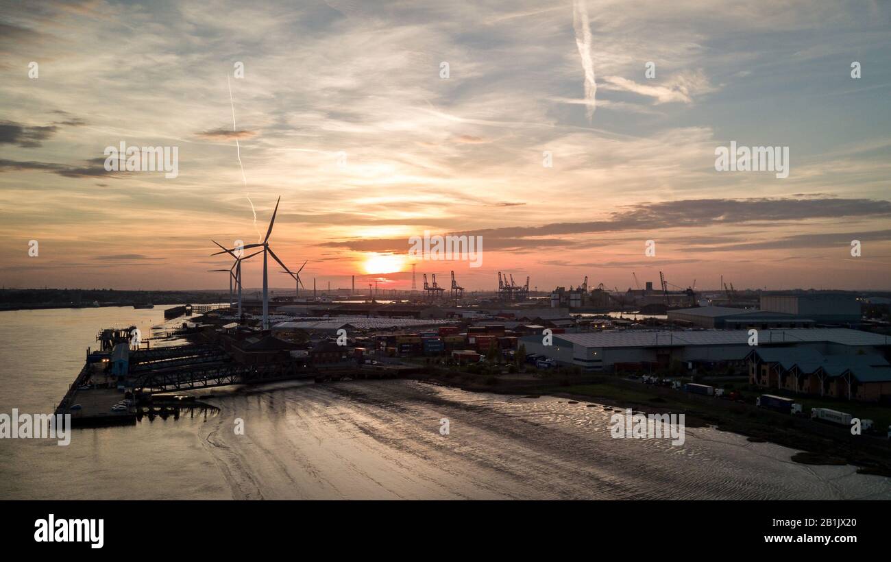 Crépuscule au port de Tilbury, Essex, Royaume-Uni. Vue sur le coucher du soleil de la marée basse de la Tamise et des éoliennes tournant en arrière-plan. Banque D'Images