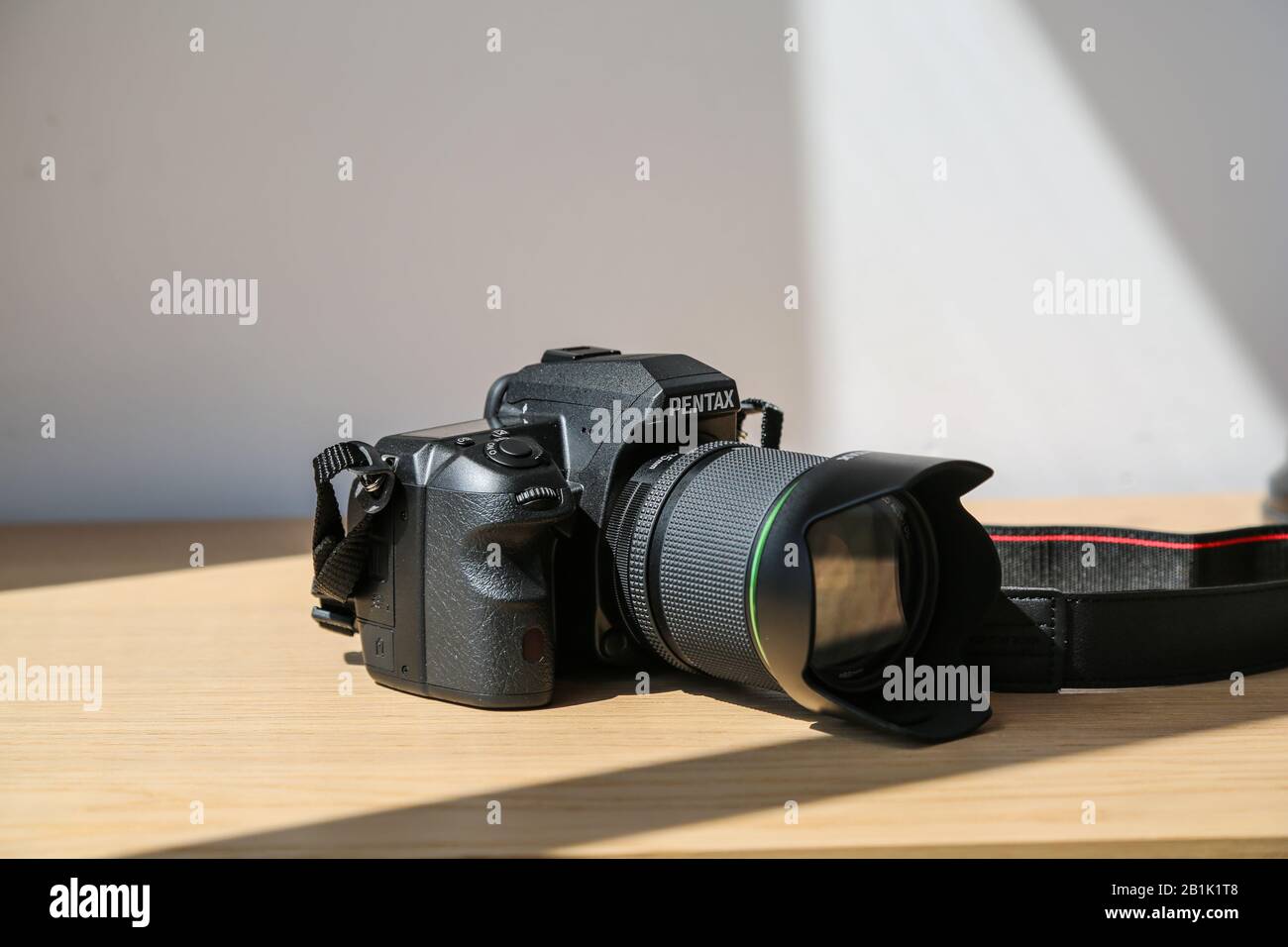 Boîtier pour appareil photo reflex numérique étanche Pentax K 3 avec kit d'objectif 18-135 mm sur table en bois sous la lumière du soleil Banque D'Images