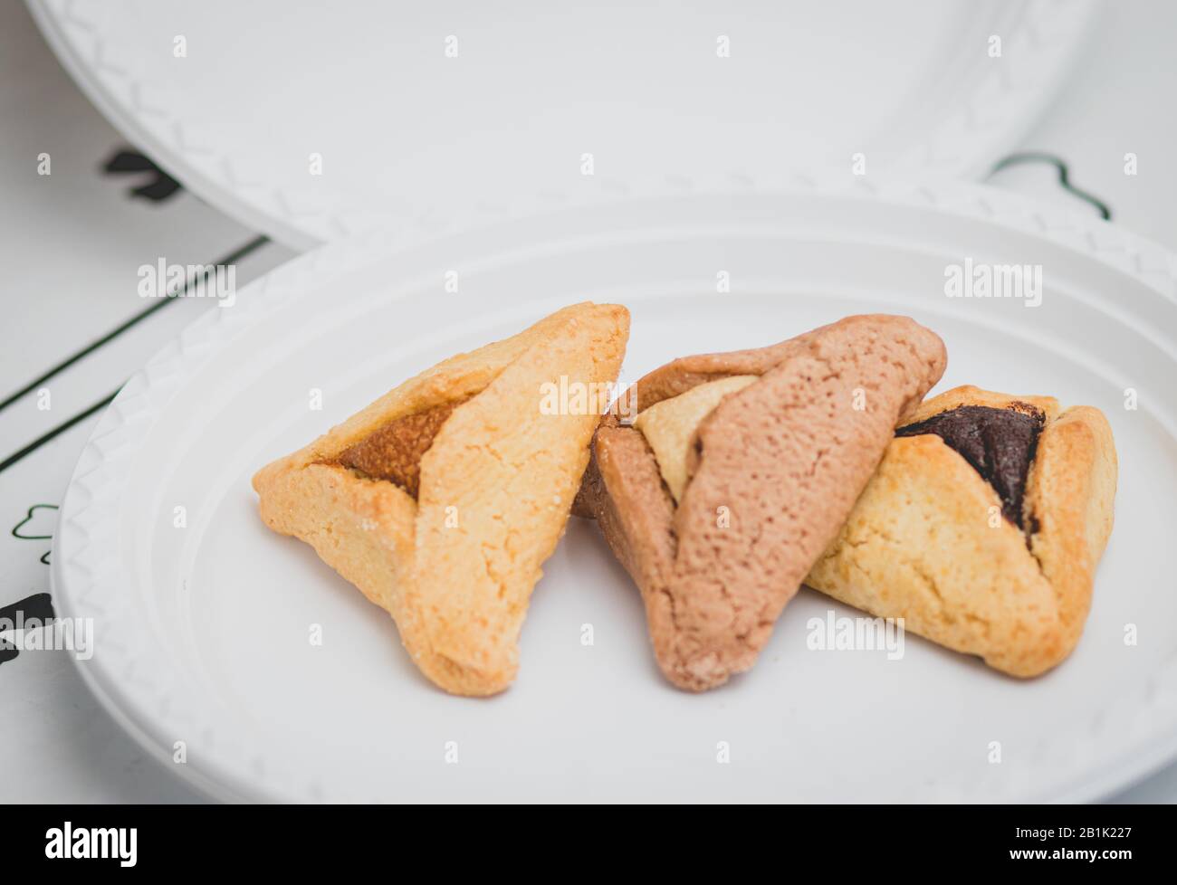 Hamantaschen. (ozen haman). La nourriture juive pour Purim. Pâte croustillante triangulaire, farcie de dattes, halva et chocolat, sur une plaque blanche. Banque D'Images