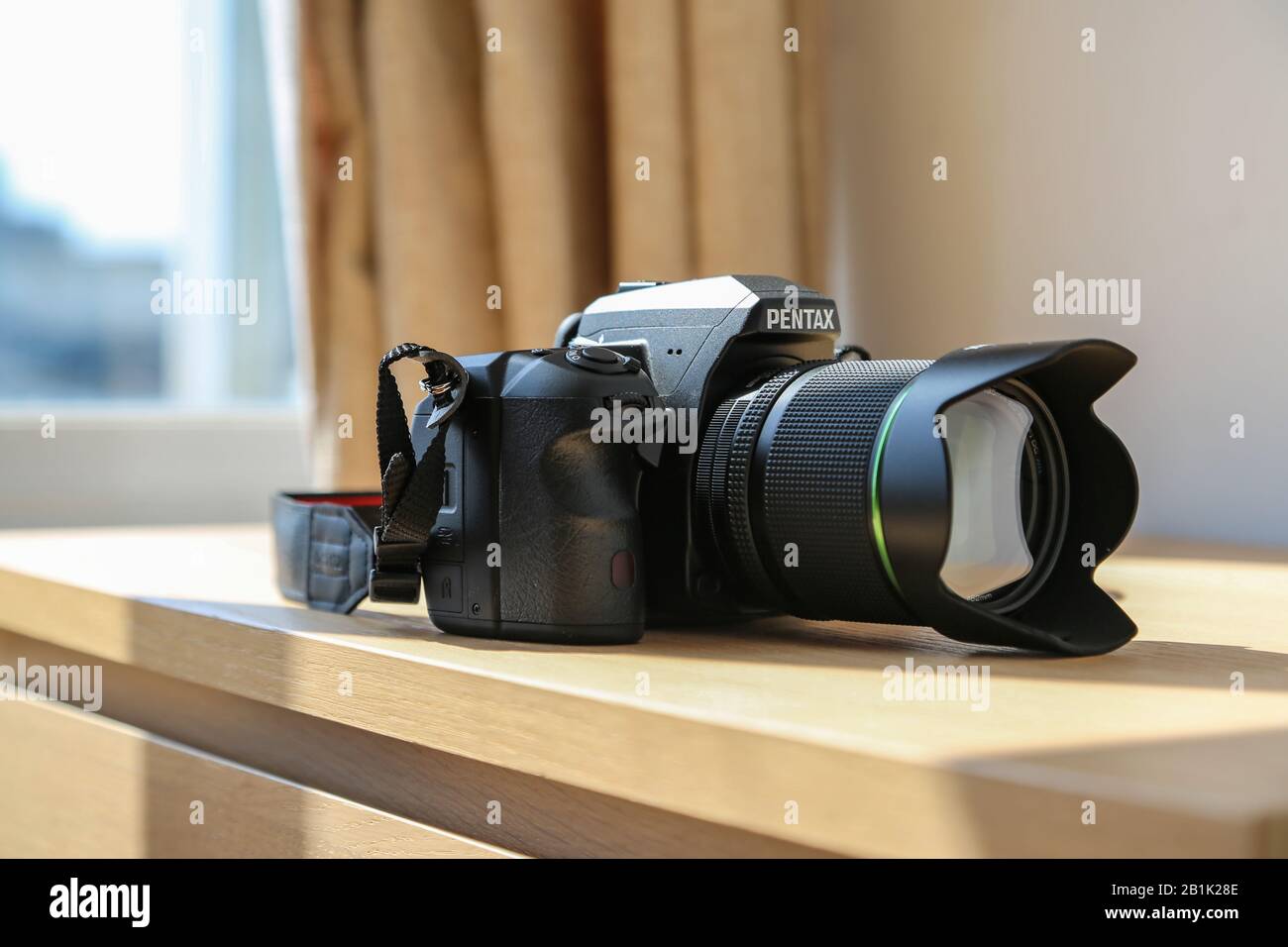 Boîtier pour appareil photo reflex numérique étanche Pentax K 3 avec kit d'objectif 18-135 mm sur table en bois sous la lumière du soleil Banque D'Images