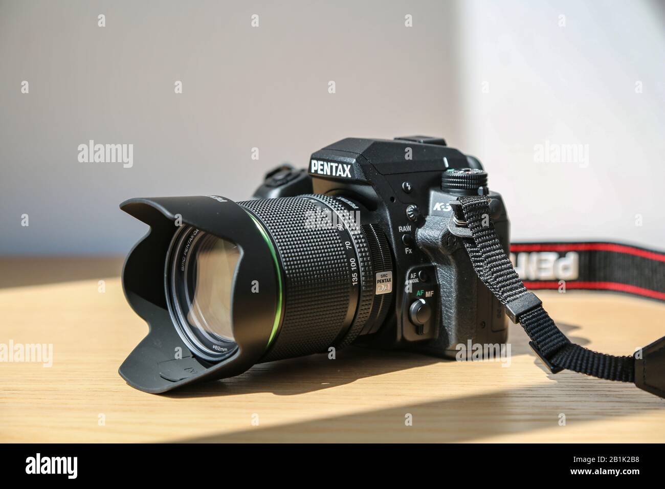Boîtier pour appareil photo reflex numérique étanche Pentax K 3 avec kit d'objectif 18-135 mm sur table en bois sous la lumière du soleil Banque D'Images