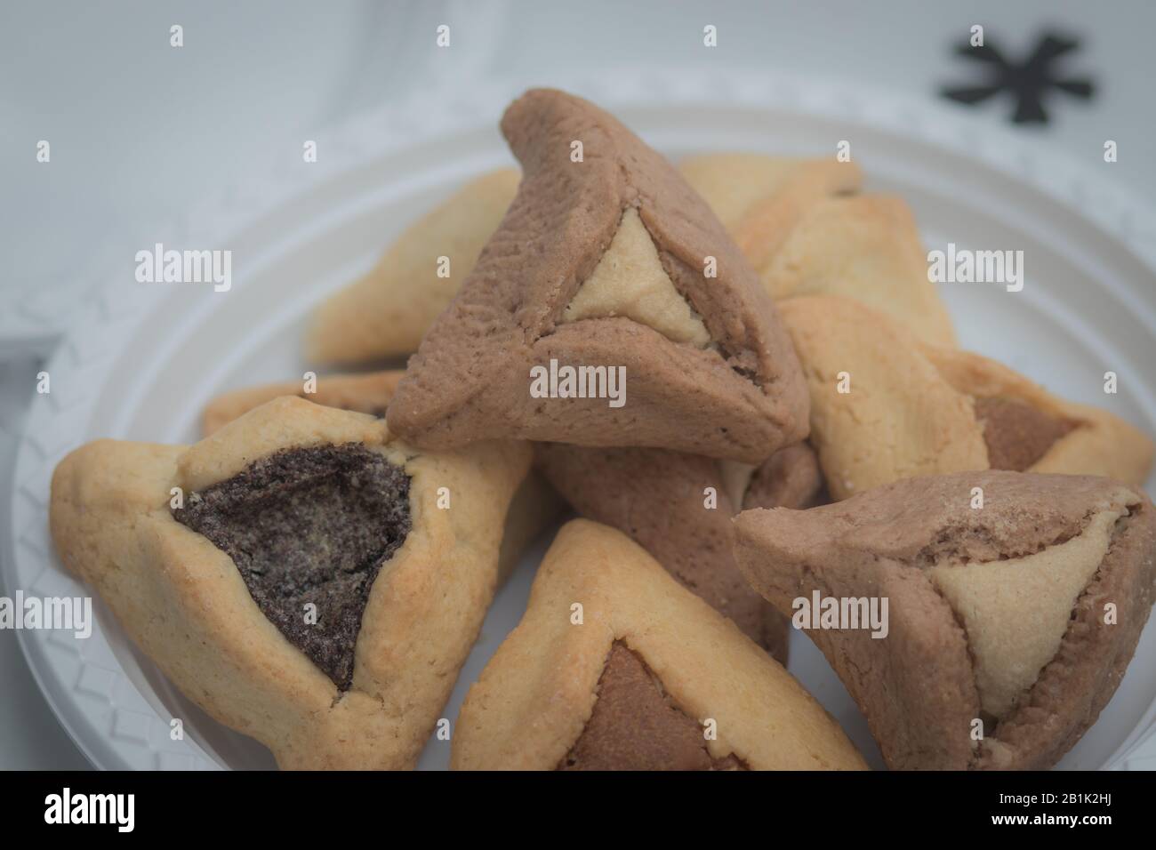 Hamantaschen. (ozen haman). La nourriture juive pour Purim. Pâte croustillante triangulaire, farcie de dattes, halva et chocolat, sur une plaque blanche. Banque D'Images