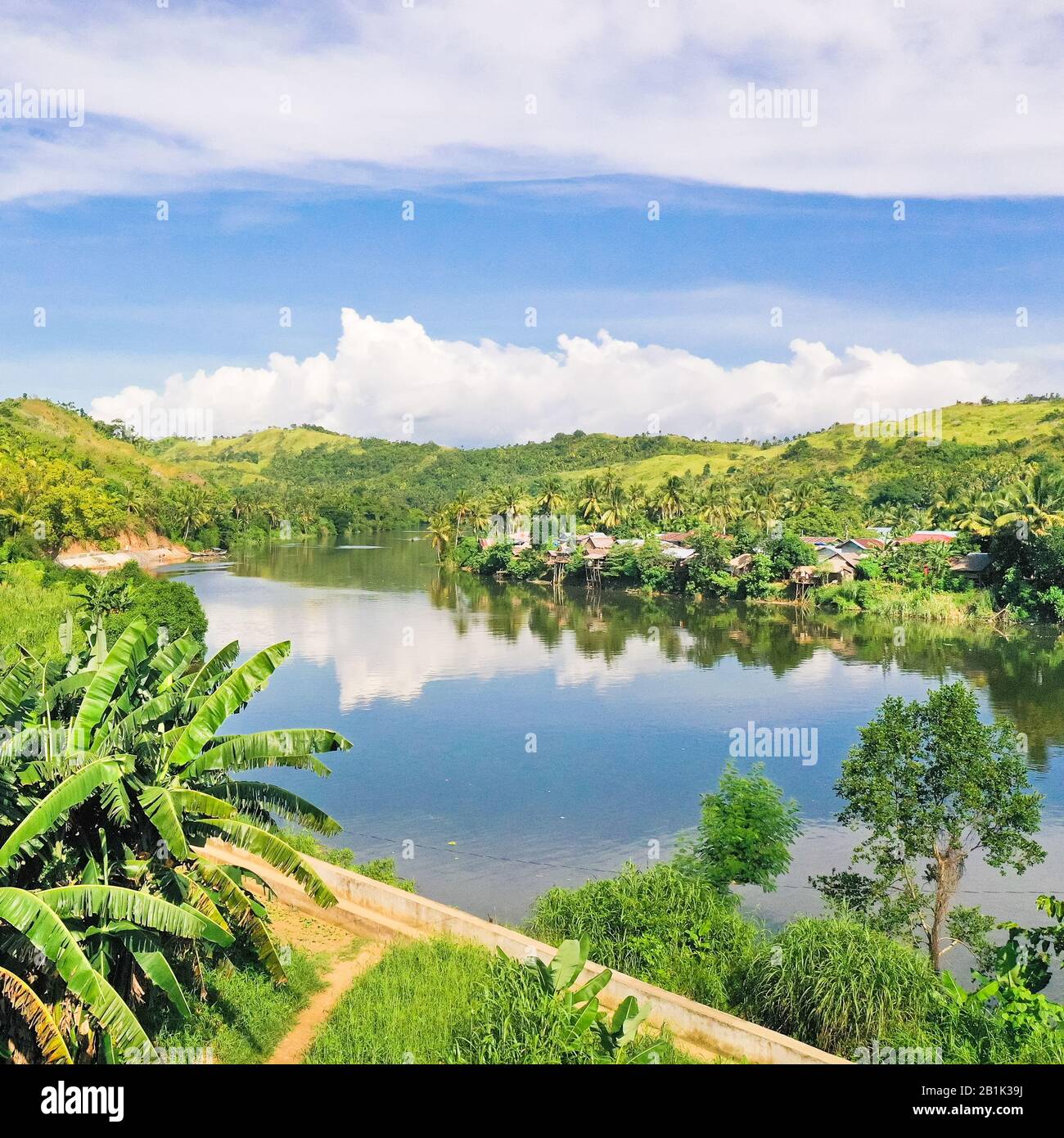 Rivière et collines vertes. Beau paysage naturel de la rivière en Asie du sud-est. Campagne sur une grande île tropicale. Petit village sur les collines vertes près de la rivière. La nature des Philippines. Banque D'Images