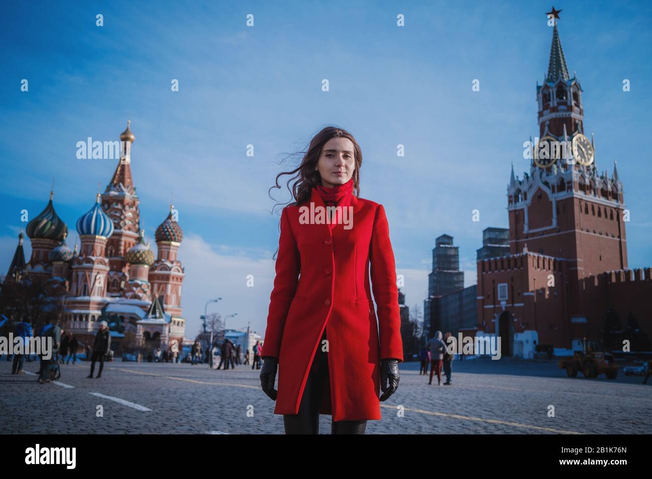 Les femmes heureuses qui marchaient dans un manteau rouge sur la place rouge de Moscou. Temps froid entre hiver et printemps, gel et soleil Banque D'Images