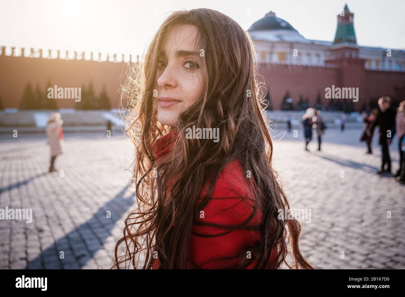 Les femmes heureuses qui marchaient dans un manteau rouge sur la place rouge de Moscou. Temps froid entre hiver et printemps, gel et soleil Banque D'Images