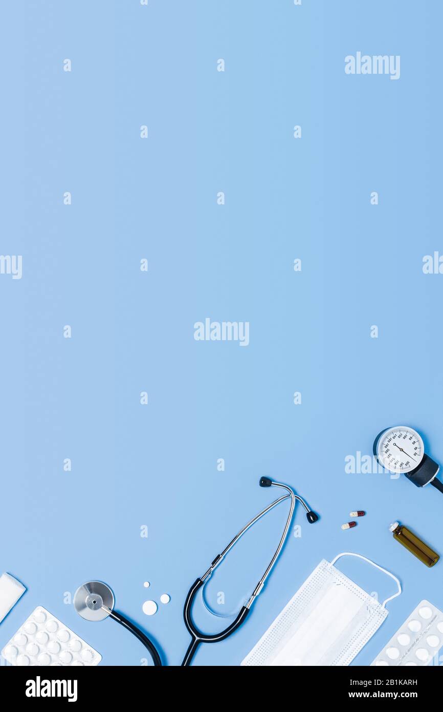 Fond vertical bleu médical avec différents accessoires : stéthoscope, thermomètre, seringue et comprimés. Banque D'Images