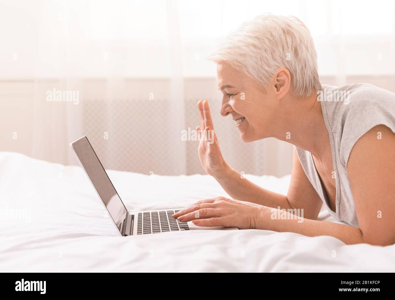 Grand-mère gaie parlant avec des parents via un ordinateur portable en ligne Banque D'Images