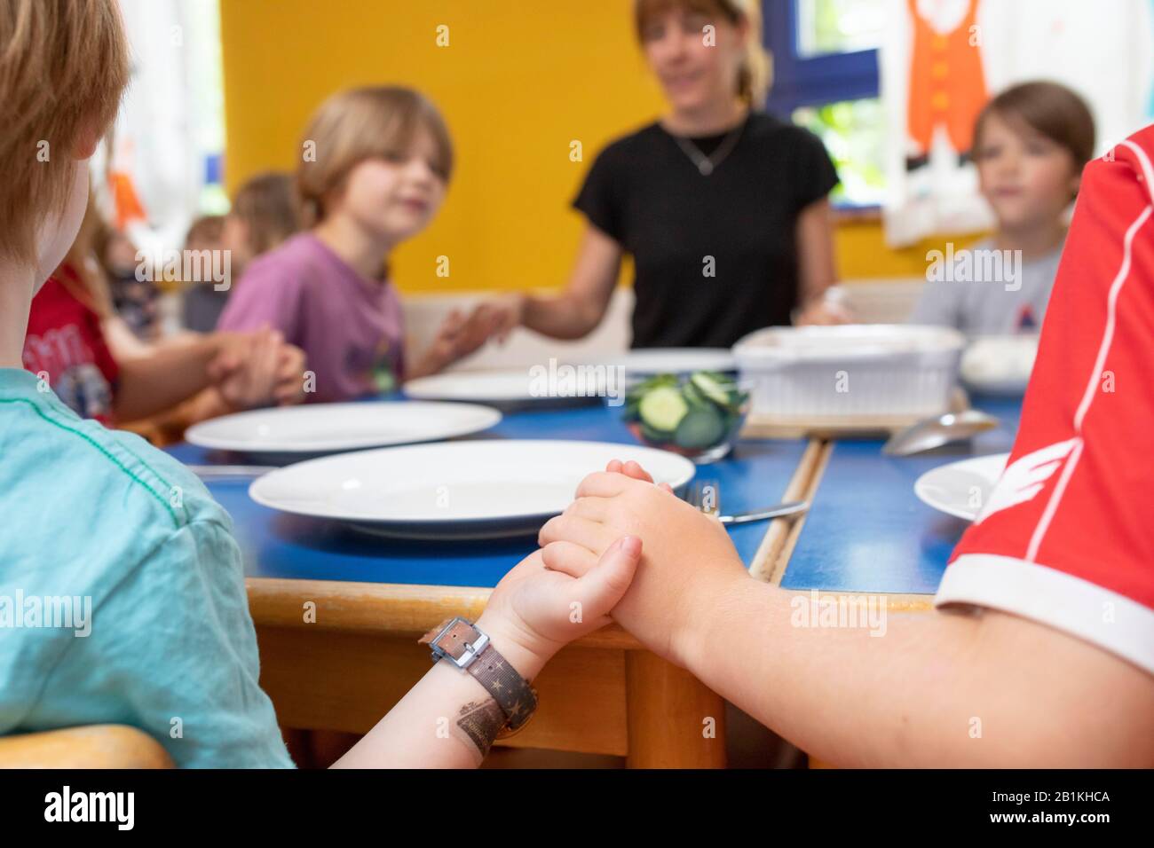 Professeur d'école maternelle et d'enfant dans la salle à manger de la maternelle tenir les mains et parler une devise de table, Cologne, Rhénanie-du-Nord-Westphalie Banque D'Images
