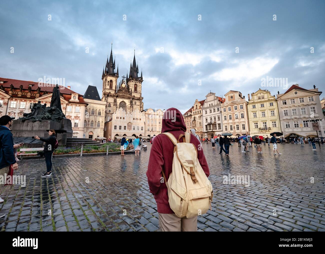 Un homme avec un sac à dos et un sweat à capuche rouge regarde par surprise la place centrale de la ville de Prague. L'idée et le concept de découvertes et de voyages Banque D'Images