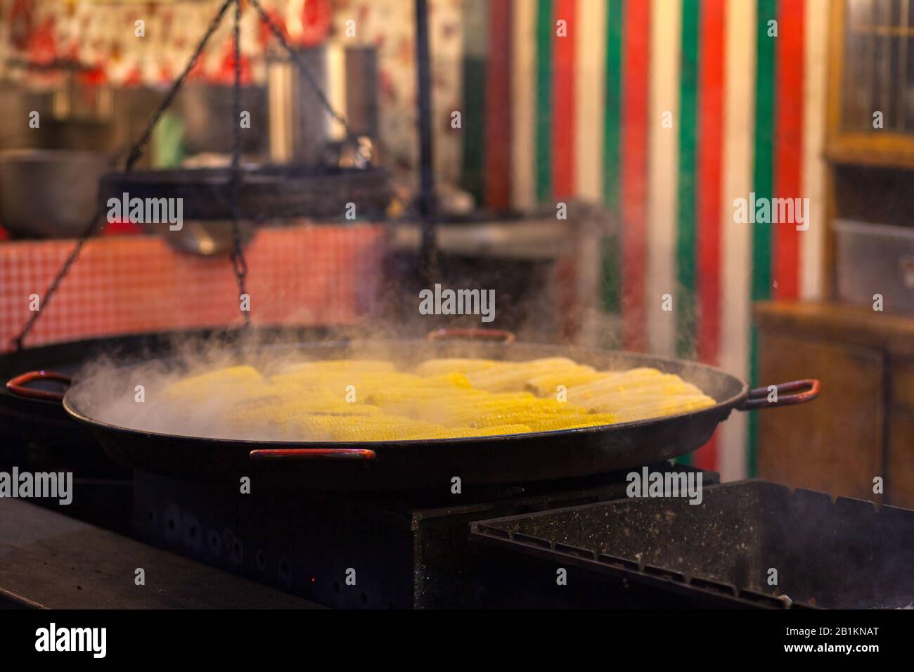 Cuisine de rue. Faire bouillir le maïs dans un grand chaudron, et l'eau bouillante épaisse s'élève au-dessus de l'eau bouillante. Dans la rue de la ville. Banque D'Images