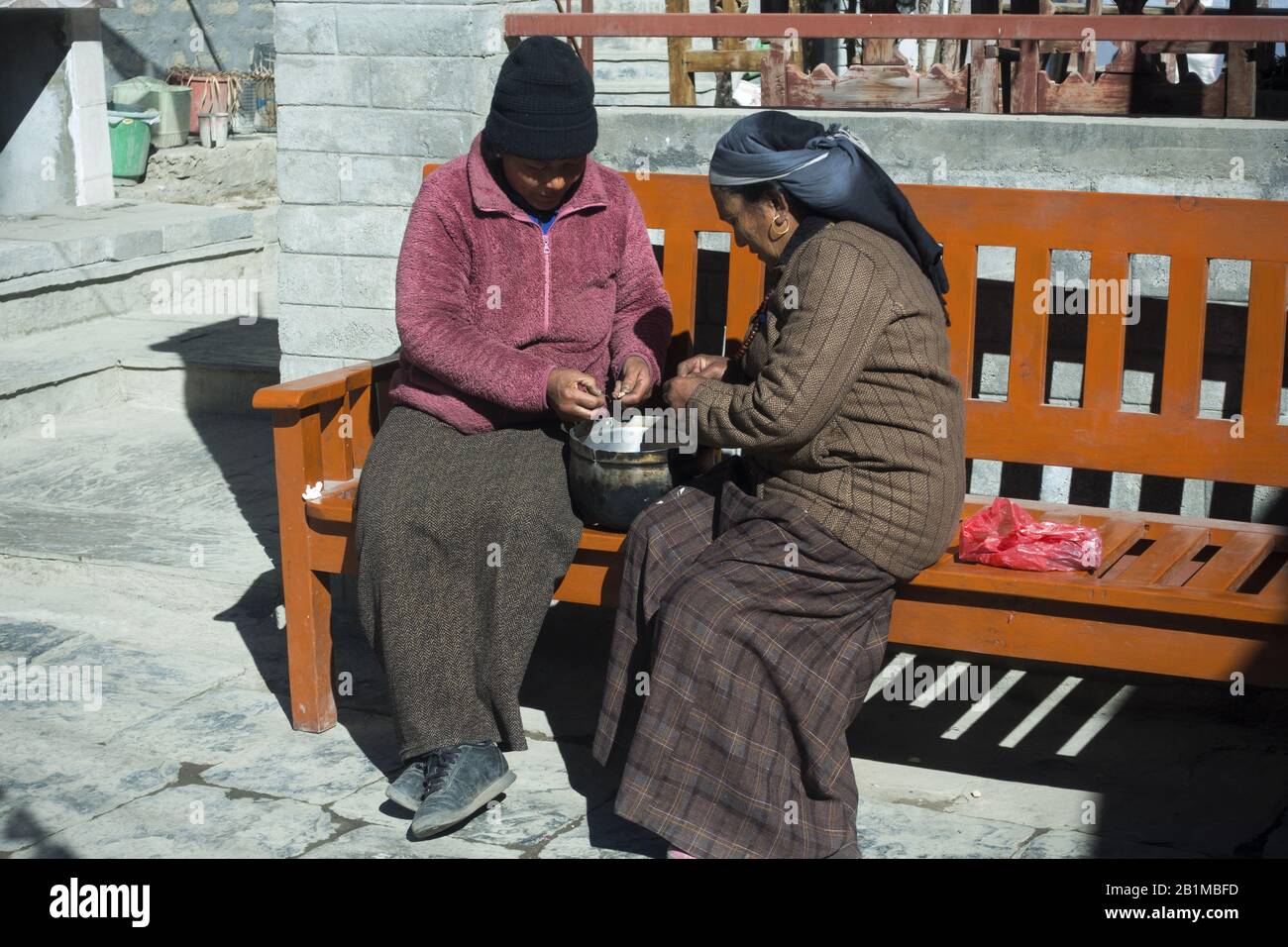 Les femmes Assises sur un banc et Faisant Des Tâches ménagères sur un soleil Chaud au Népal Himalaya Mountain Village Banque D'Images