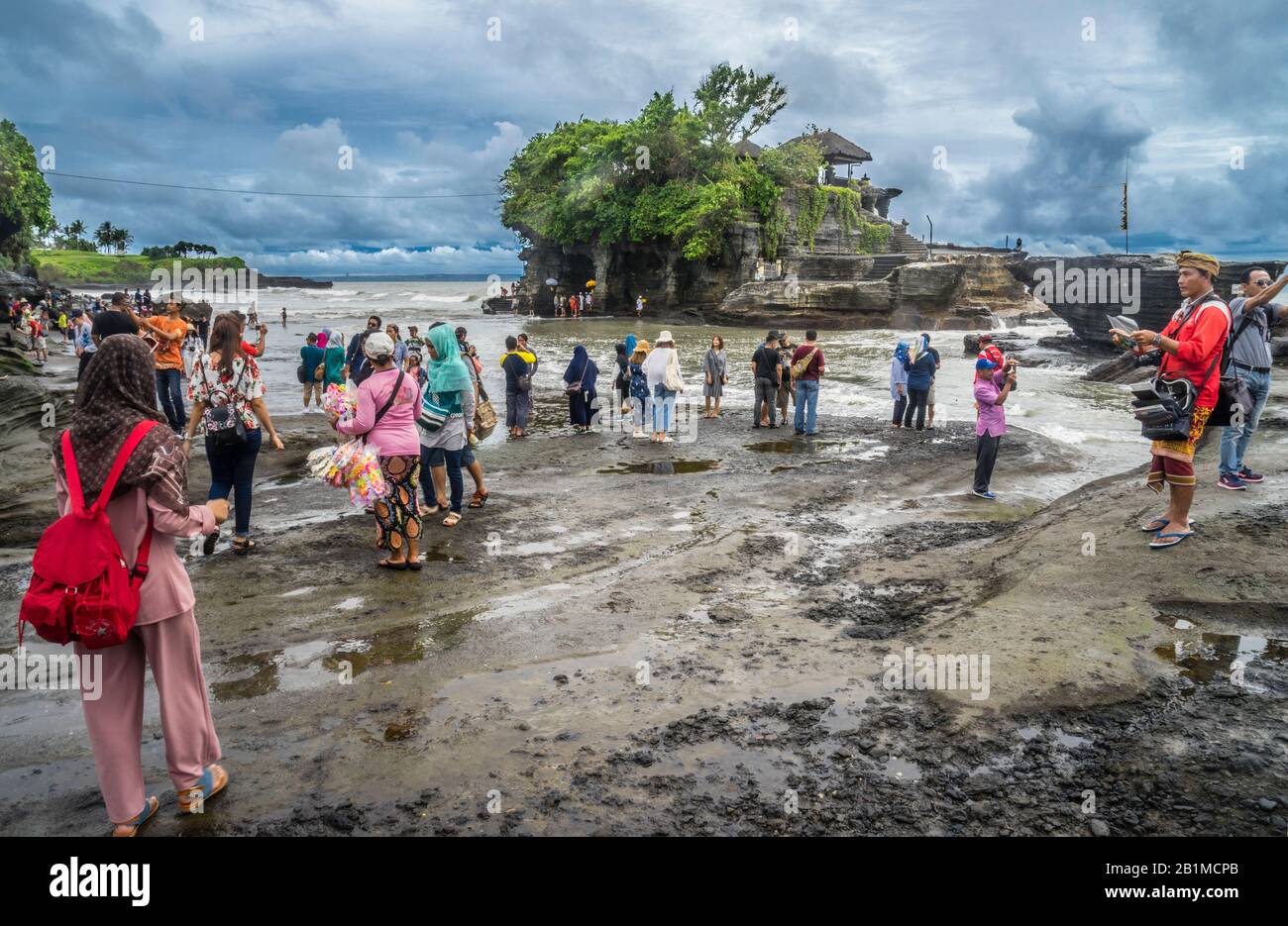 Visiteurs et pèlerins à Tanah Lot, une formation de roches au large de l'île indonésienne de Bali, qui abrite un ancien temple de pèlerinage hindou Pura Tanah Lot, Bal Banque D'Images
