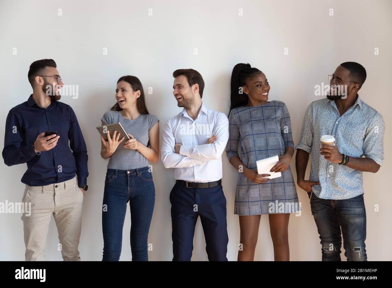 Les gens d'affaires joyeux et variés qui bavardent se sentent heureux de poser isolé sur le gris Banque D'Images