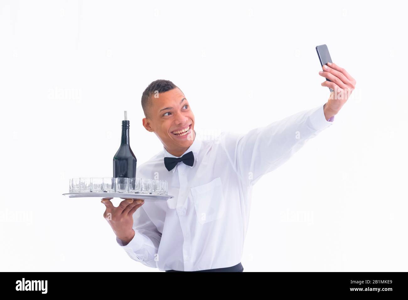 Serveur tenant un plateau et en utilisant son téléphone Banque D'Images