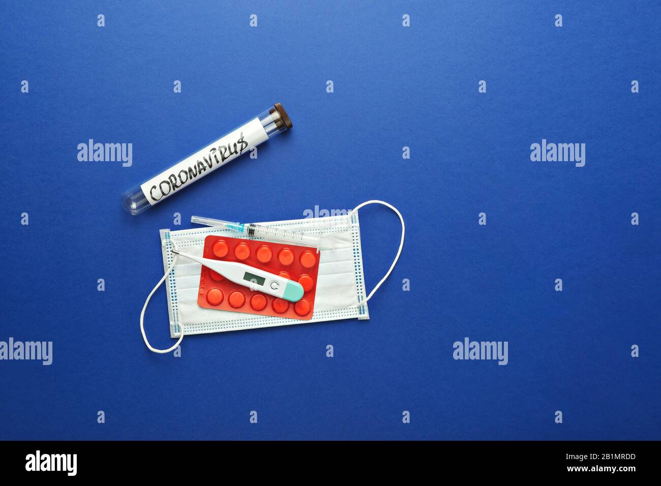 Thermomètre, seringue, masque chirurgical, pilules et vaccin antigrippal dans le tube d'essai en bleu. Chinois wuhan COVID-19 concept de méthodes de protection contre les virus, plat Banque D'Images