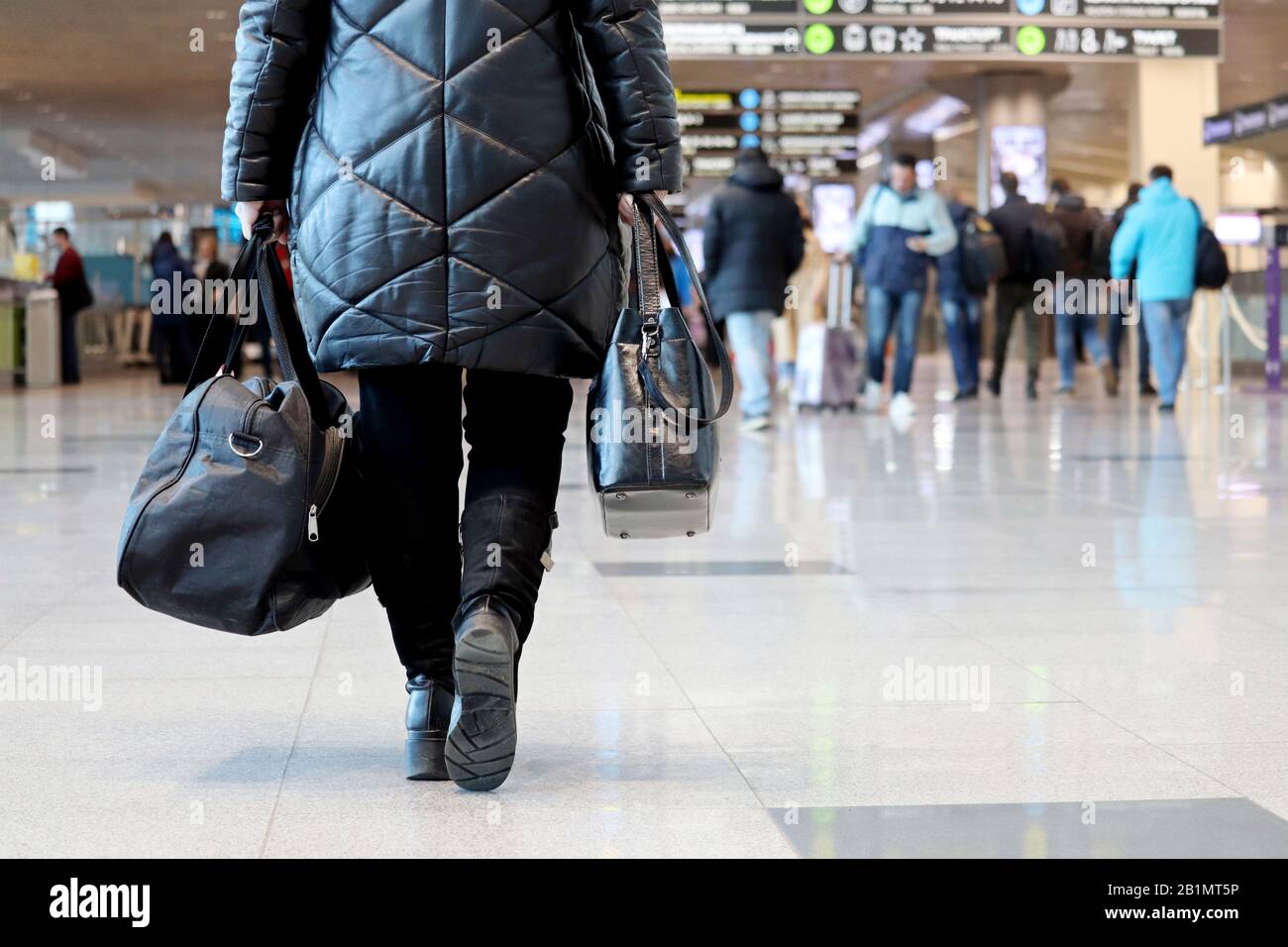 Femme avec des bagages à main marchant à l'intérieur du bâtiment de l'aéroport sur l'arrière-plan des passagers. Concept de voyageur avant de flotter Banque D'Images