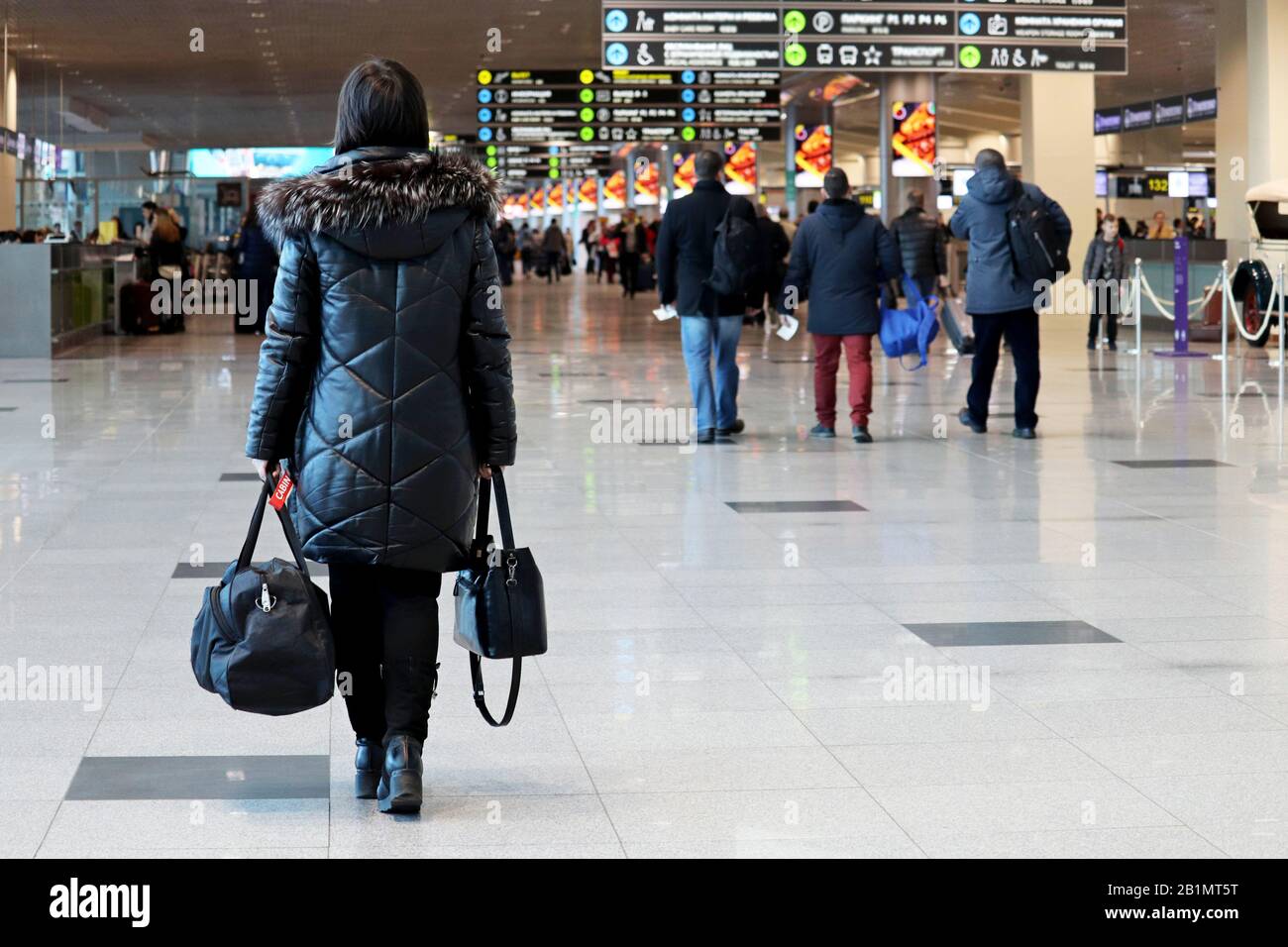 Femme avec des bagages à main marchant à l'intérieur du bâtiment de l'aéroport sur l'arrière-plan des passagers. Concept de voyageur avant de flotter Banque D'Images