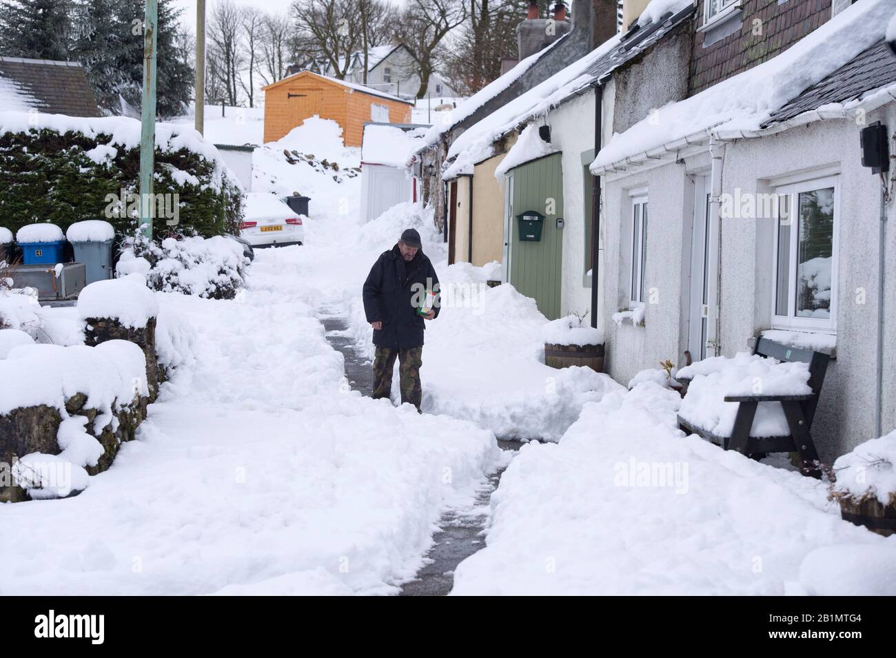 Un homme descend une rue enneigée dans le village de Leadhills, South Lanarkshire, Ecosse. Banque D'Images