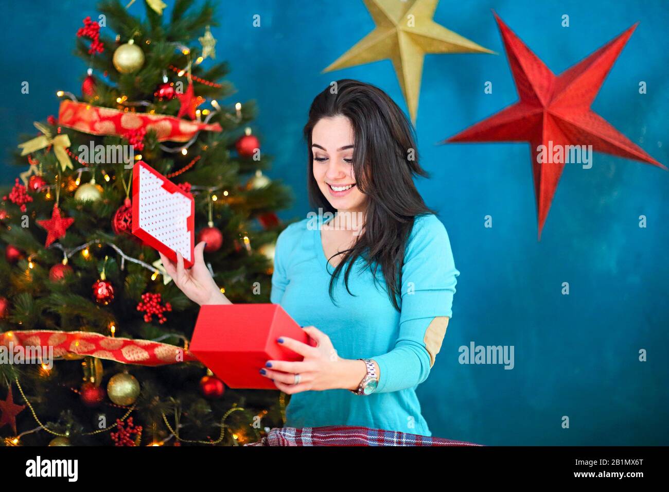 Smiling woman with gift box au salon sur fond d'arbre de Noël. Les vacances et les personnes concept. Temps de Noël Banque D'Images