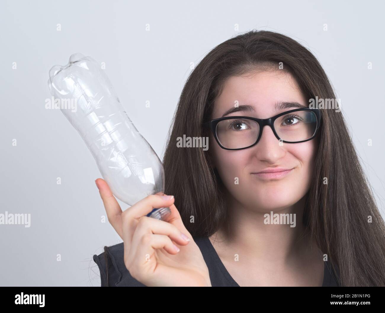 Portrait d'une Brunette Teen Girl à poil long et bessectacite avec bouteille en plastique Banque D'Images