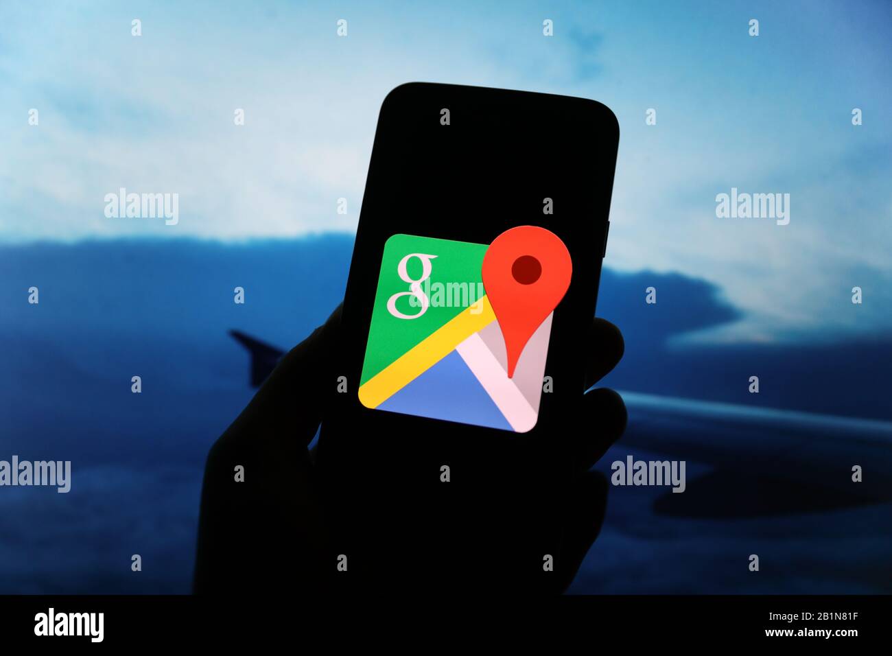 Le logo Google s'affiche sur l'écran du smartphone avec une vue de l'avion et une aile d'avion visible floue en arrière-plan Banque D'Images
