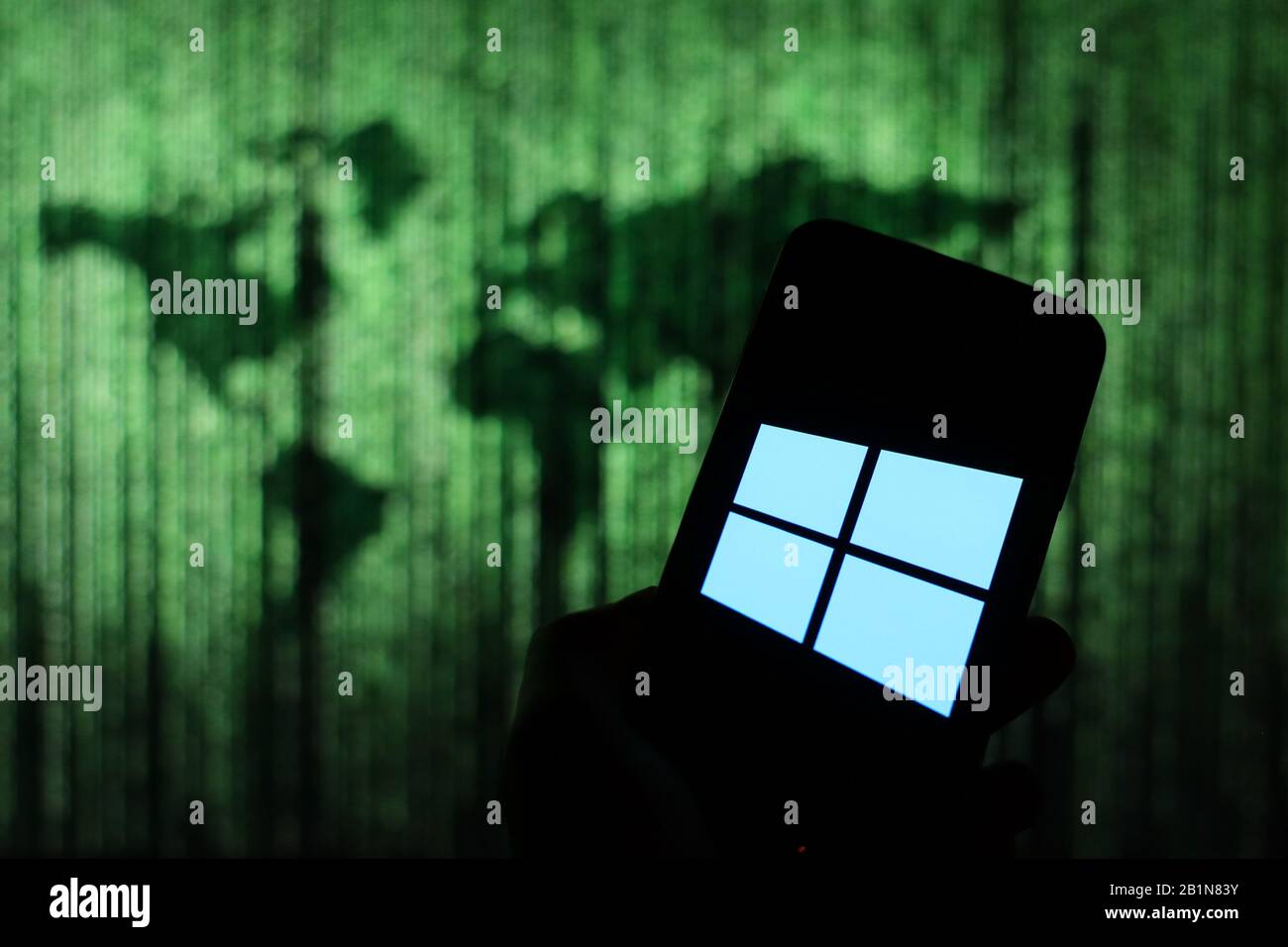 Logo Microsoft Windows 10 affiché sur l'écran du smartphone avec une carte du monde de type matrice visible floue en arrière-plan Banque D'Images