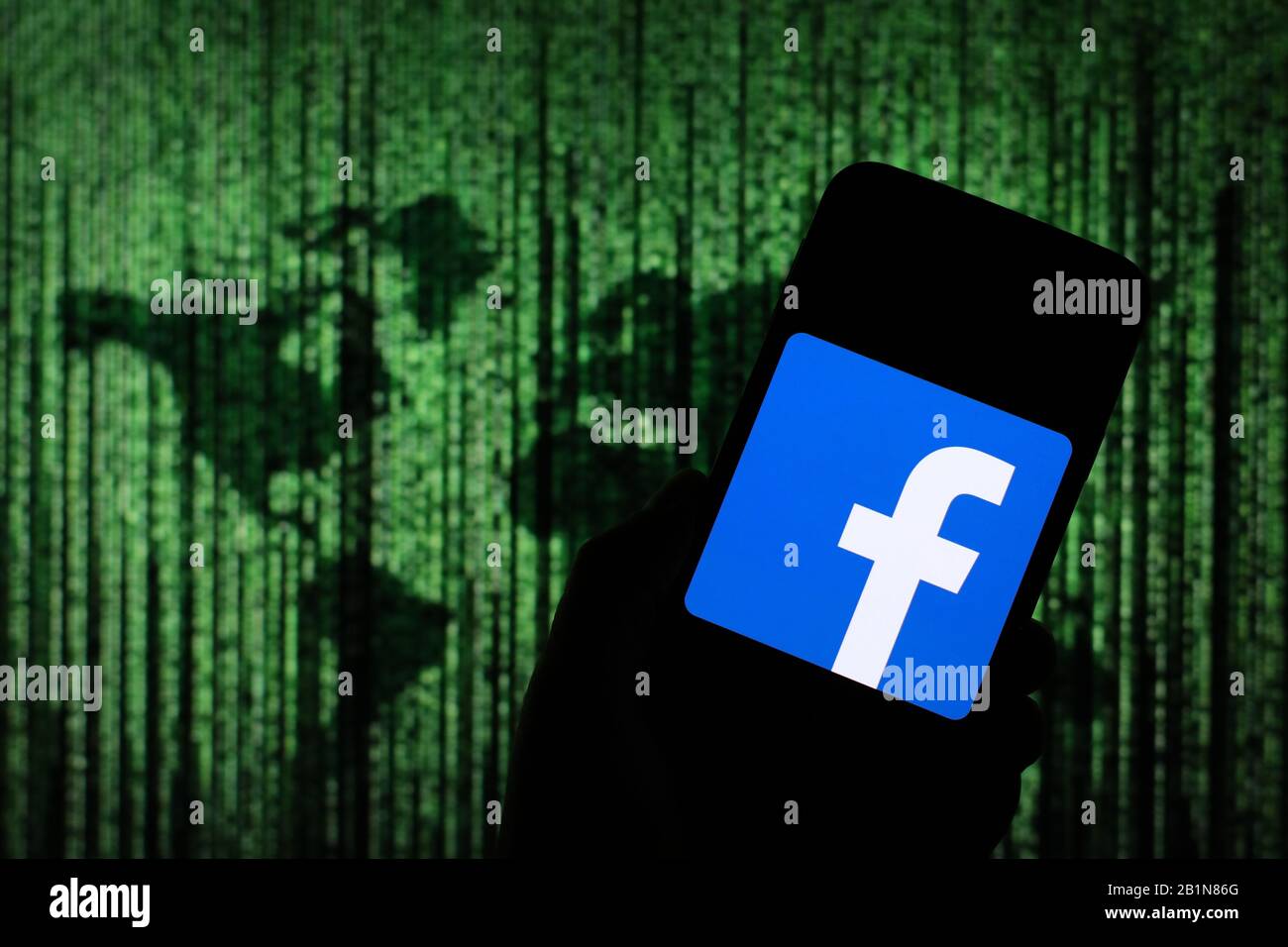 Logo Facebook affiché sur l'écran du smartphone avec une carte du monde de type matrice visible floue en arrière-plan Banque D'Images
