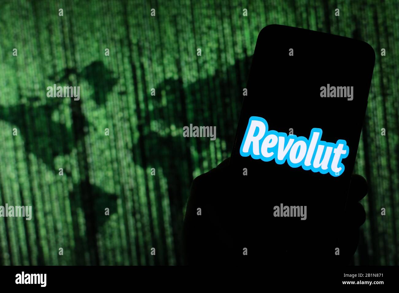 Le logo Revolut Online Money Exchange Company s'affiche sur l'écran du smartphone avec une carte du monde de type matrice visible floue en arrière-plan Banque D'Images