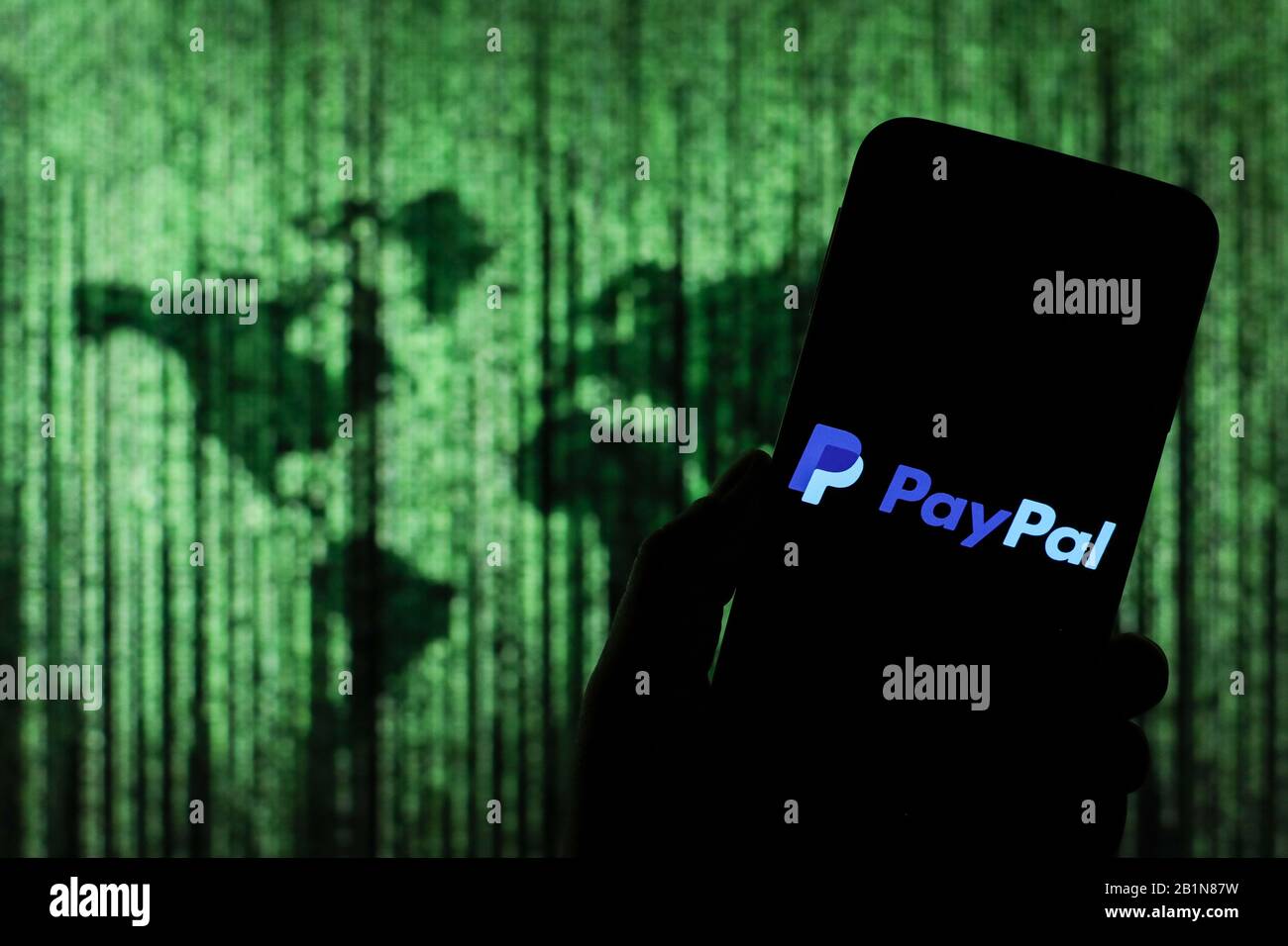 Le logo de la société d'échange d'argent en ligne PayPal s'affiche sur l'écran du smartphone avec une carte du monde de type matrice visible floue en arrière-plan Banque D'Images