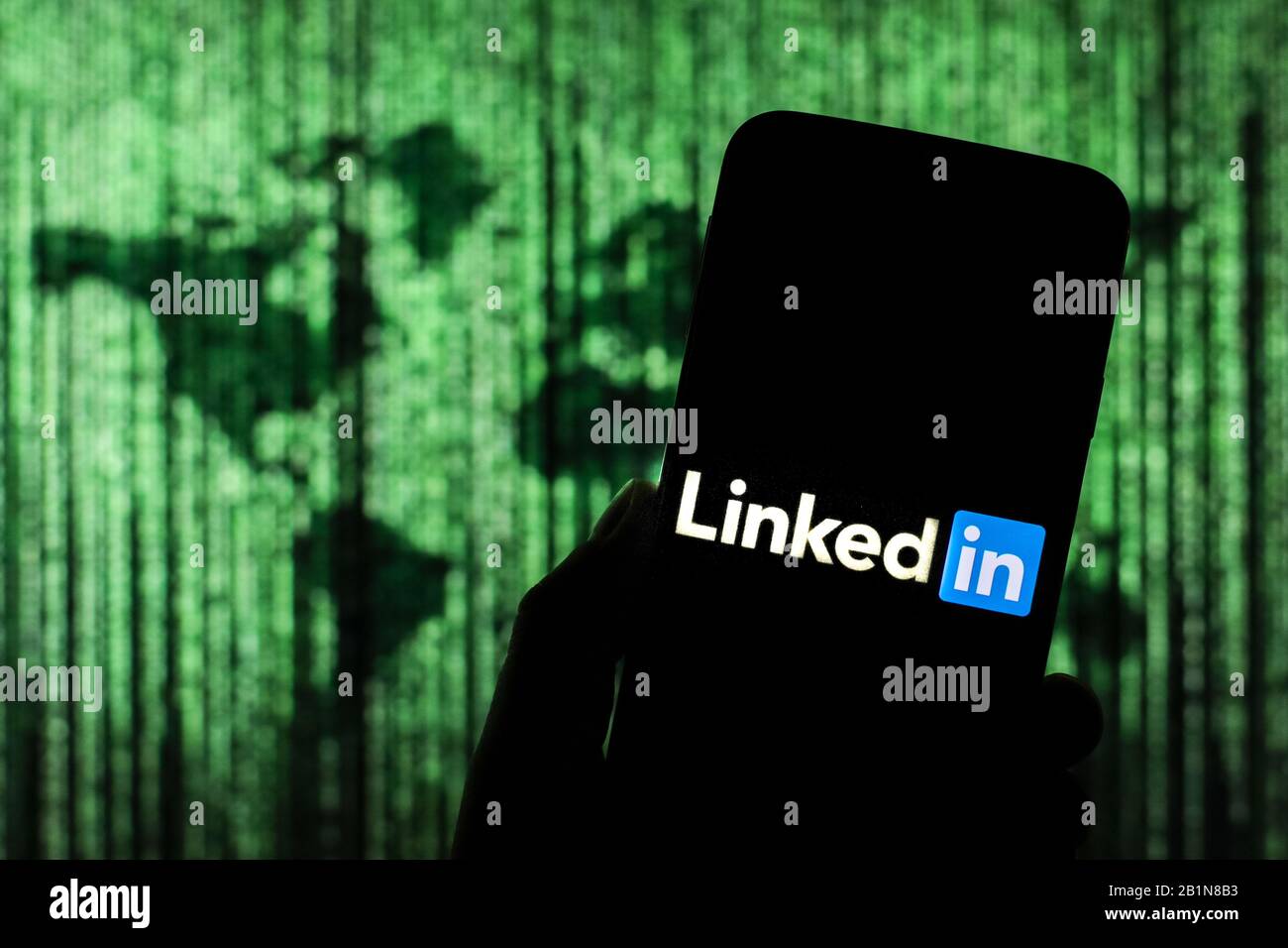 Lié Au logo du site Web des réseaux sociaux affiché sur l'écran du smartphone avec une carte du monde de type matrice visible floue en arrière-plan Banque D'Images