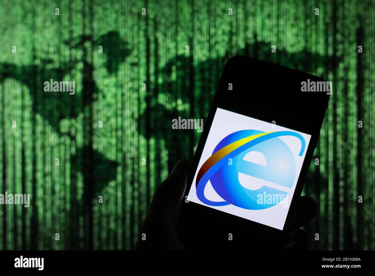 Le logo du navigateur Web d'Internet Explorer s'affiche sur l'écran du smartphone avec une carte du monde de type matrice visible floue en arrière-plan Banque D'Images