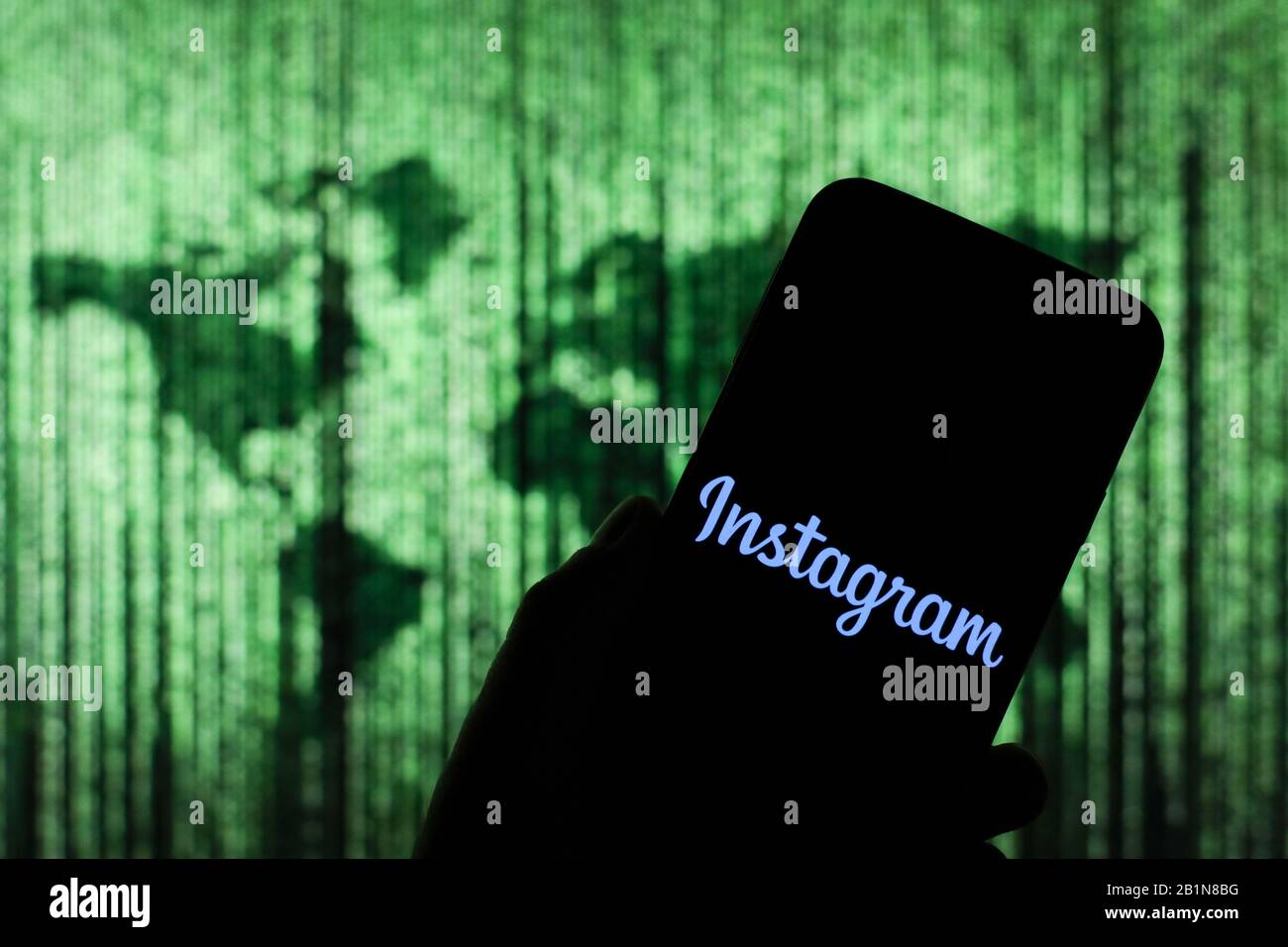 Logo Instagram affiché sur l'écran du smartphone avec une carte du monde de type matrice visible floue en arrière-plan Banque D'Images