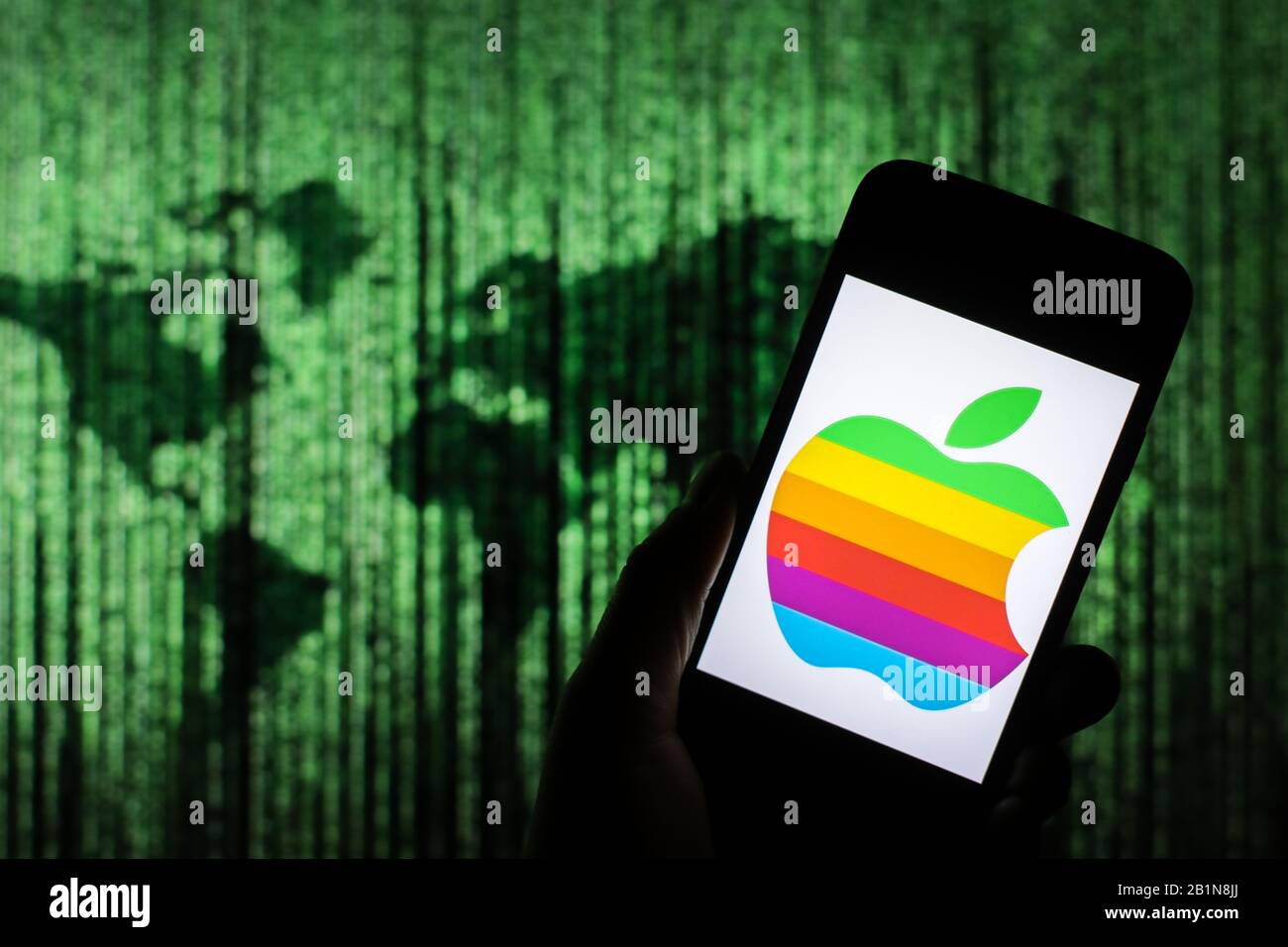 Logo coloré Apple affiché sur l'écran du smartphone avec une carte du monde de type matrice visible floue en arrière-plan Banque D'Images
