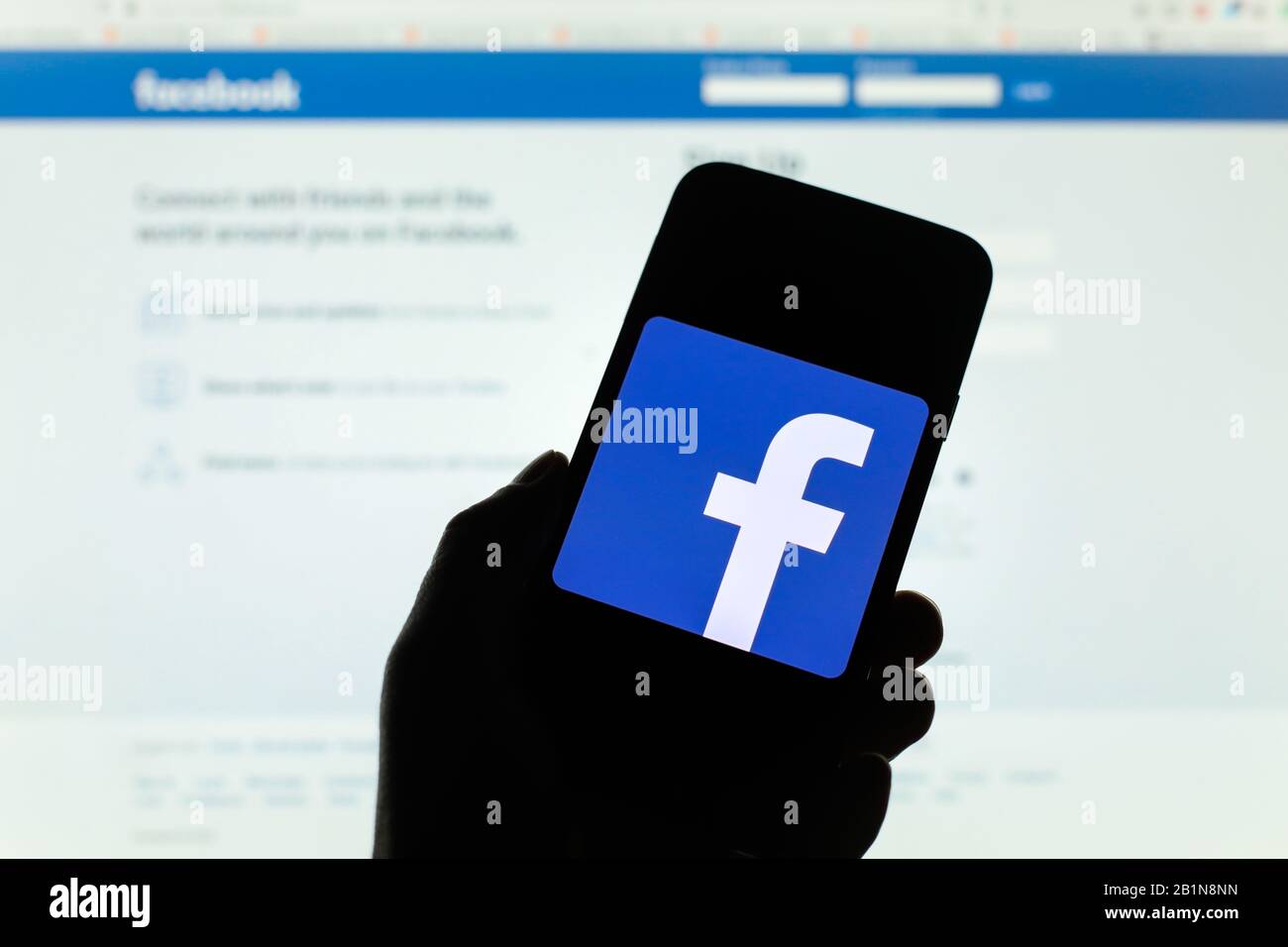 Logo de la société Facebook affiché sur l'écran du smartphone avec écran d'accueil Facebook visible flou en arrière-plan Banque D'Images