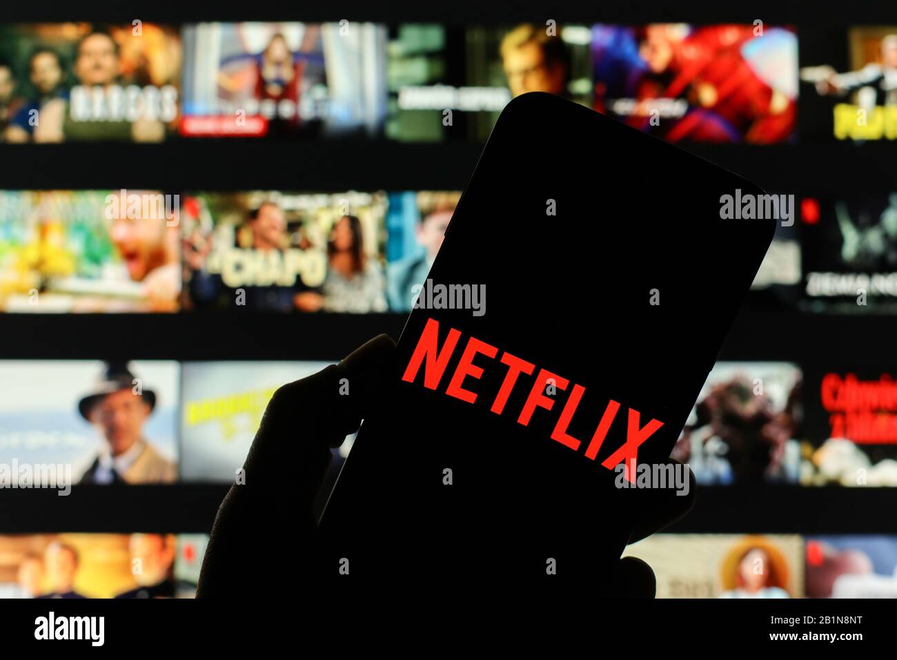 Le logo de la société Netflix s'affiche sur l'écran du smartphone avec l'écran d'accueil Netflix visible flou en arrière-plan Banque D'Images