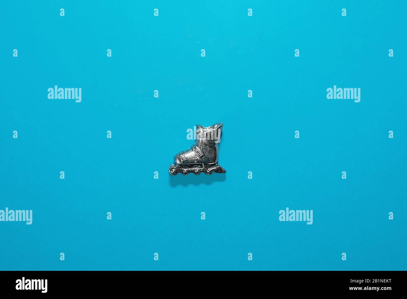 une figurine métallique de patins à roulettes est factice sur un fond bleu clair avec une ombre dure. Mise à plat, vue de dessus, mise en page Banque D'Images
