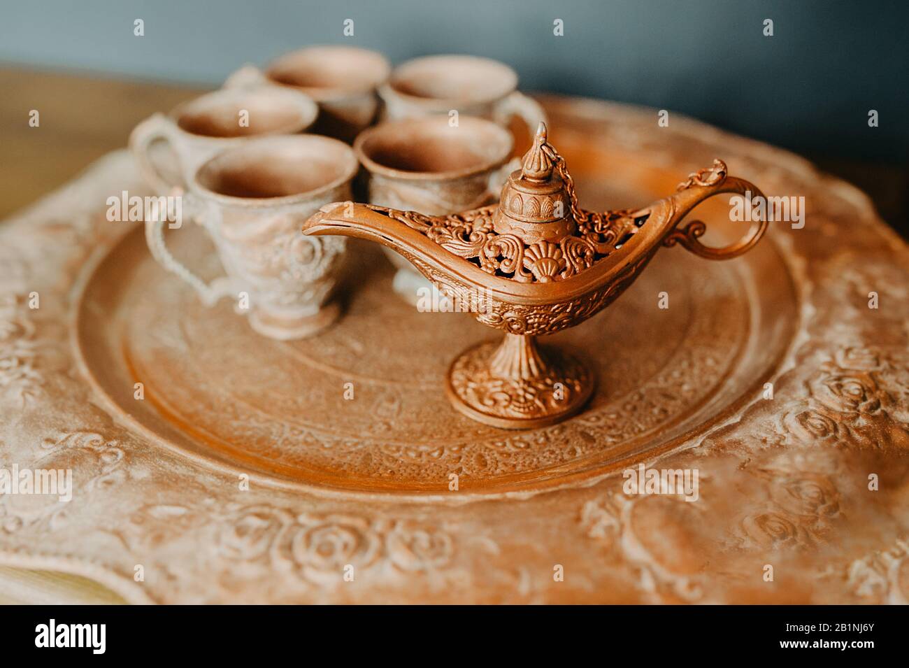 Lampe magique orientale en métal doré de Gin sur un vieux plateau doré sur le fond de petites tasses Banque D'Images