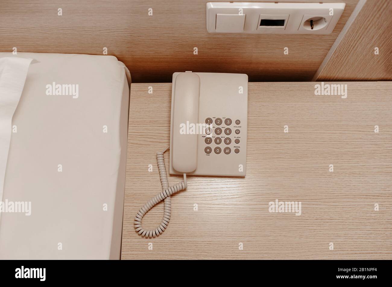 ce n'est pas un téléphone moderne avec fil blanc et boutons sur une table de chevet en bois beige Banque D'Images