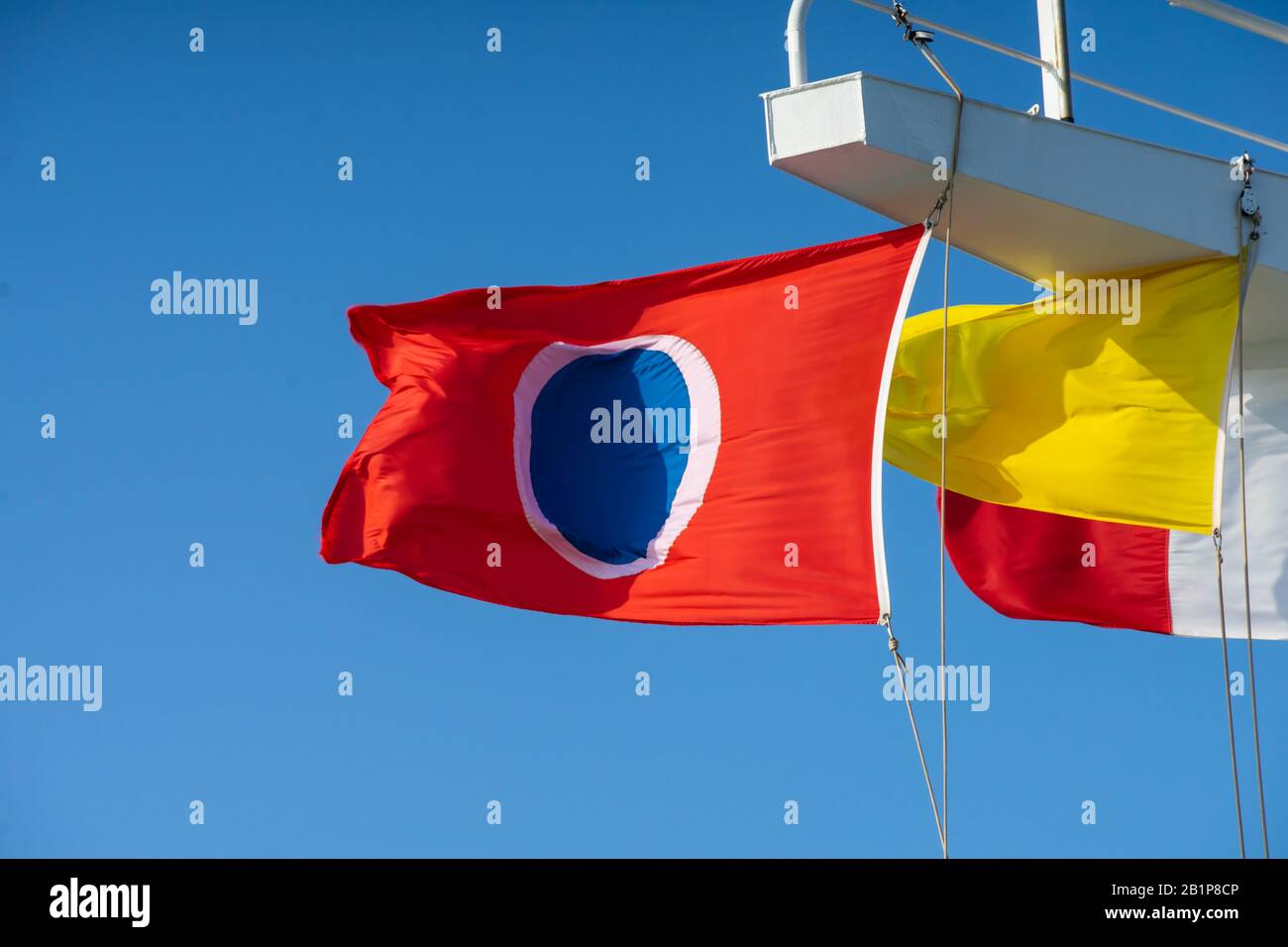 Drapeau rouge bleu et blanc de la ligne de croisière de Carnaval volant dans des vents forts sur une journée bleue sur un bateau de croisière Banque D'Images