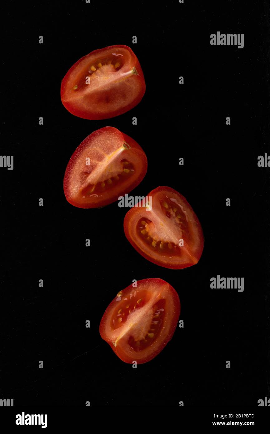 Tomates cerises. Quatre tranches de tomates cerises en pierre noire. Banque D'Images