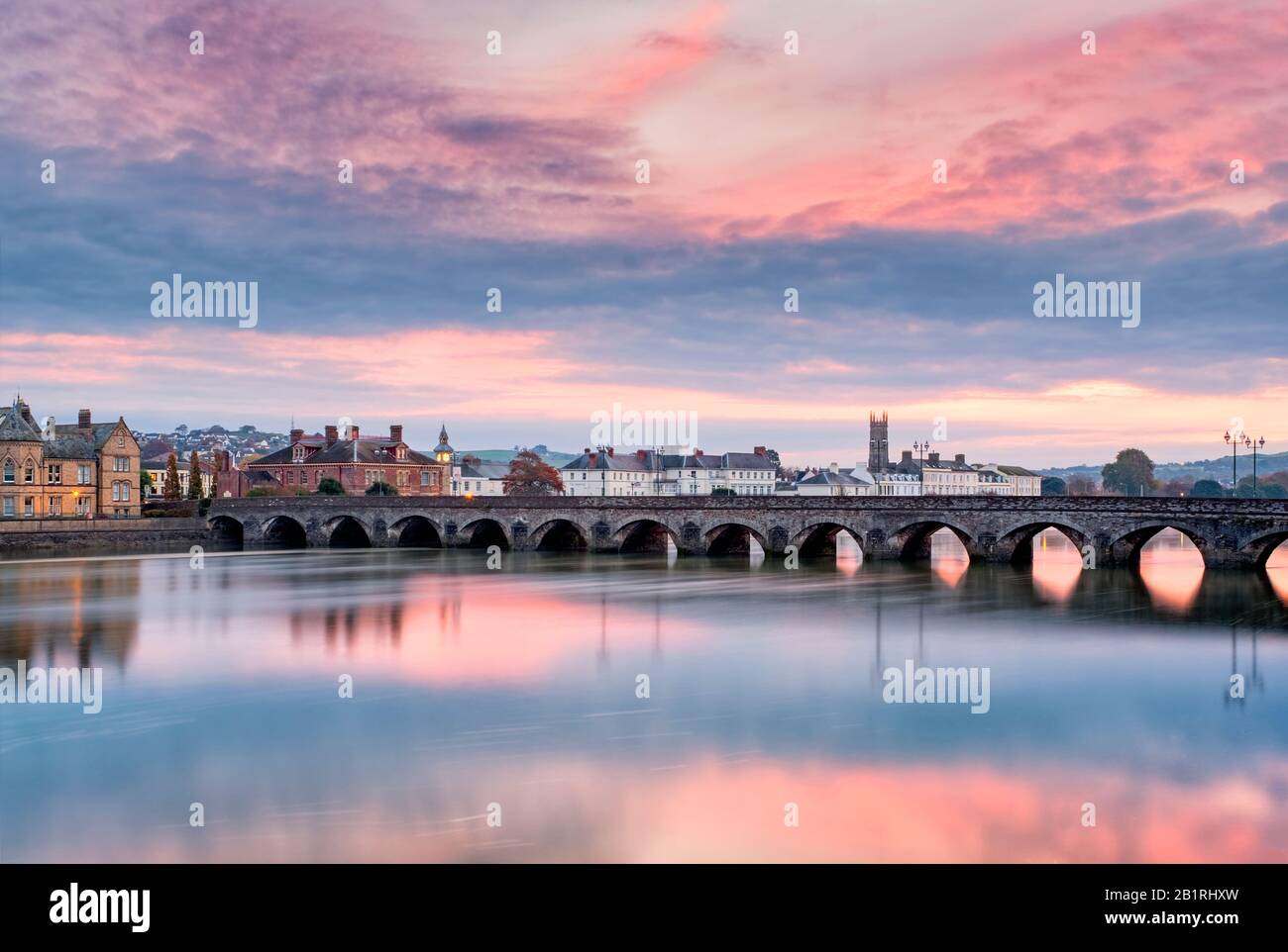 Ciel rose au lever du soleil sur le Barnstaple, pont long médiéval, au-dessus de la rivière Taw , North Devon, South West, Royaume-Uni Banque D'Images